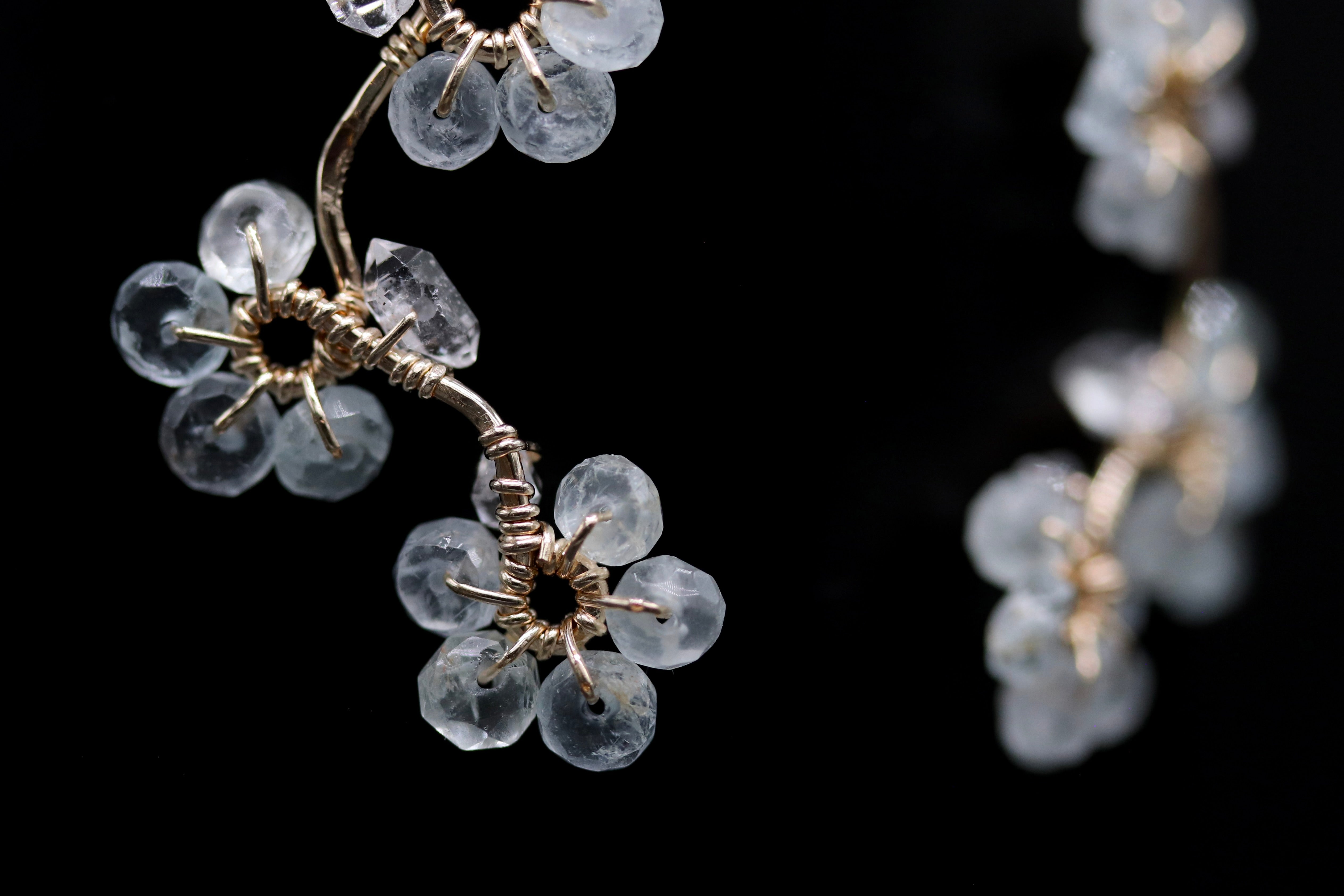A close-up view of a delicate, crystal-like flower-shaped ornament with intricate metalwork, set against a dark background.