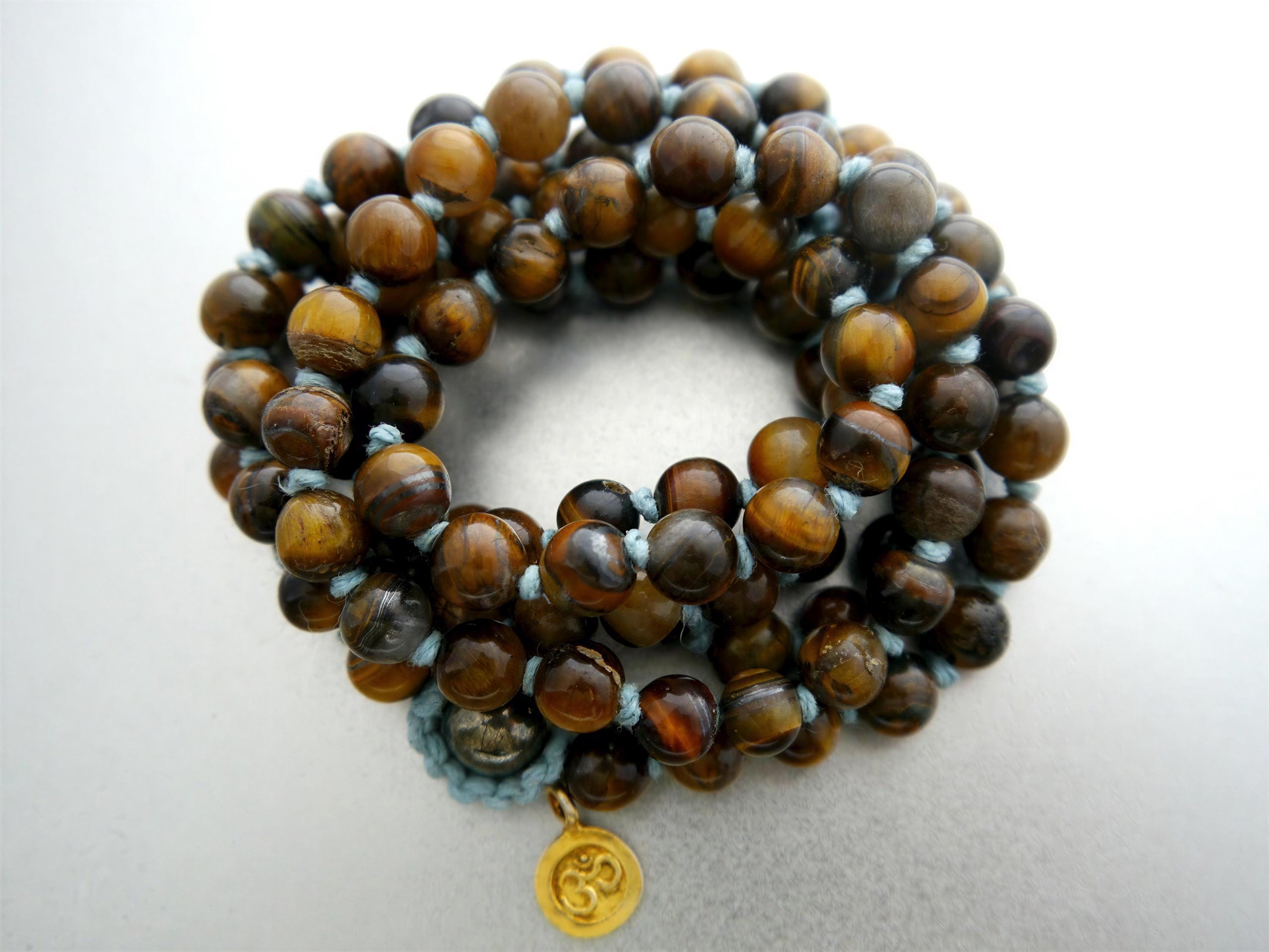 A beaded bracelet with a gold charm, featuring a circular arrangement of brown and black beads.
