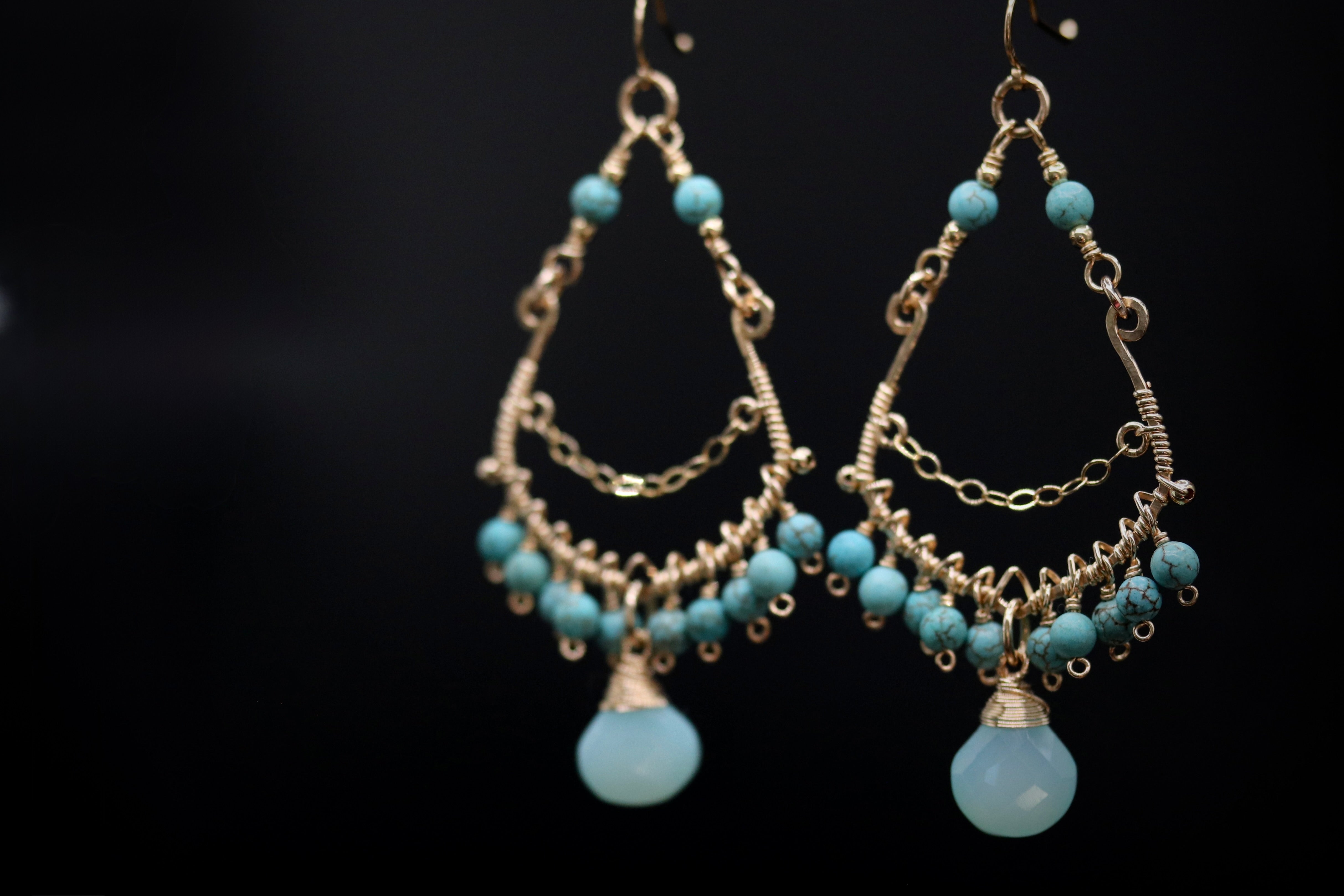 A pair of elegant earrings with turquoise beads and intricate gold metalwork.