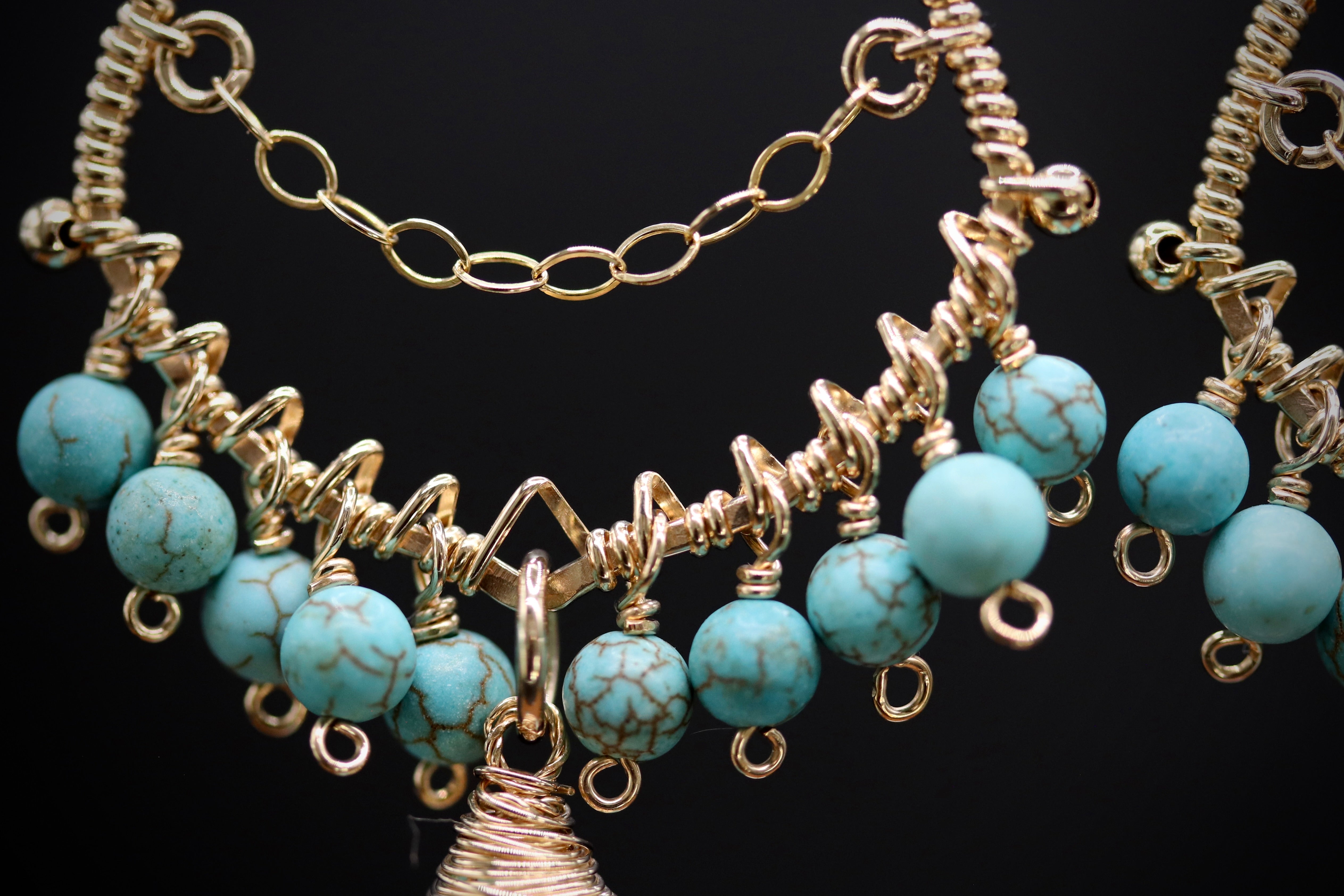 A close-up view of a necklace with turquoise beads and gold-colored metal chains.