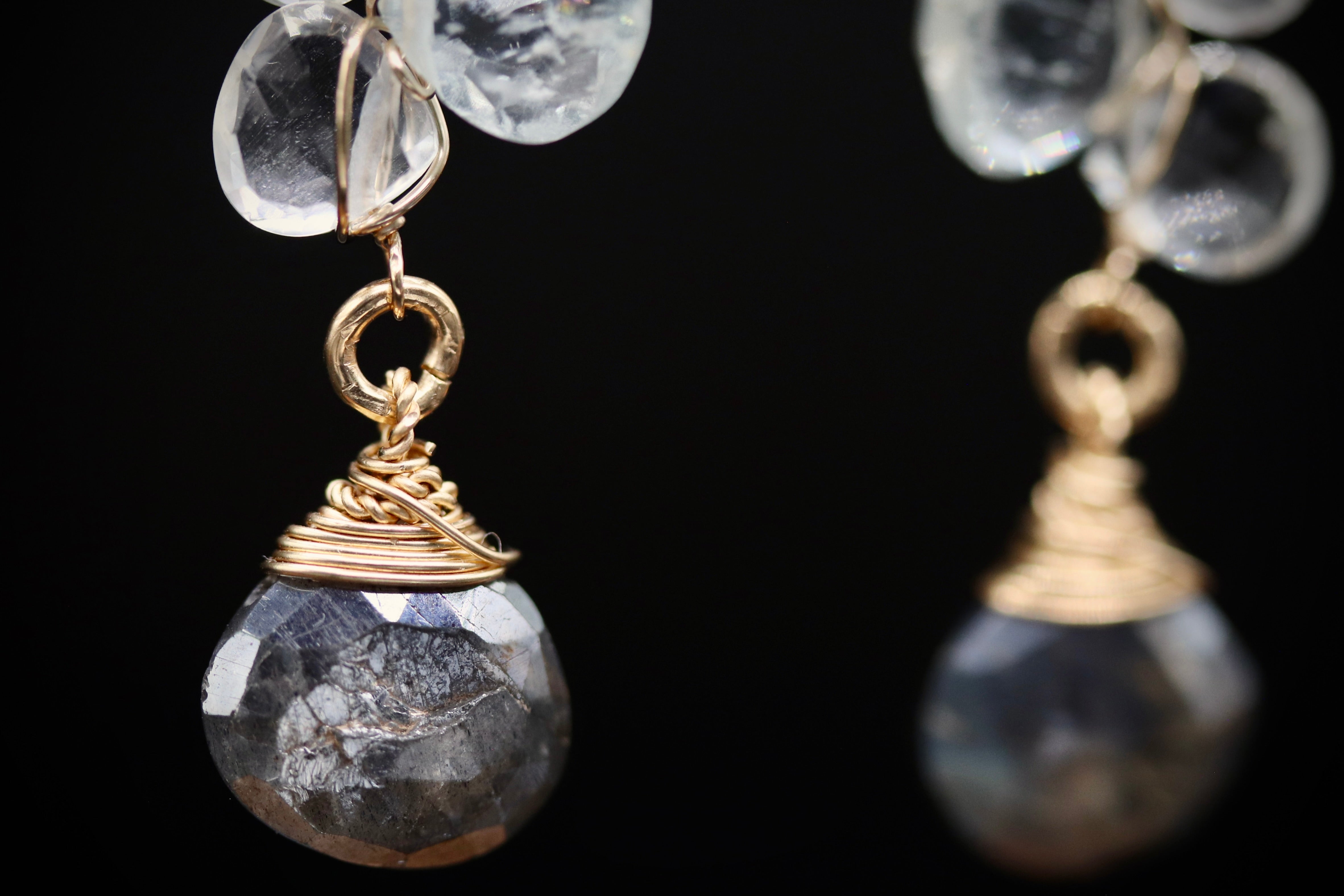 A close-up view of a pair of elegant earrings with clear gemstone pendants and gold-colored metal accents.