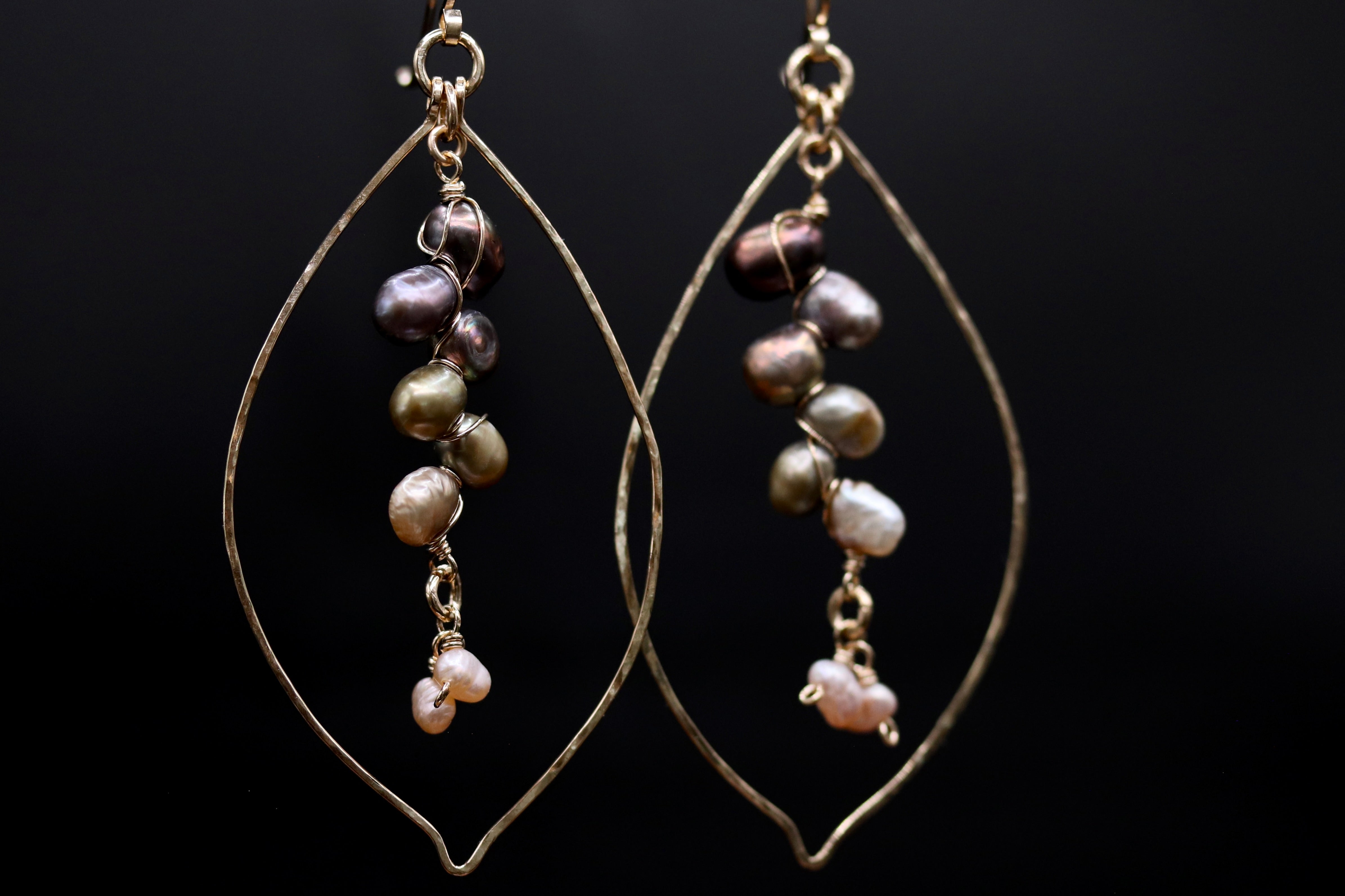 A pair of gold earrings with a dangling design, featuring a variety of colored pearls and beads.