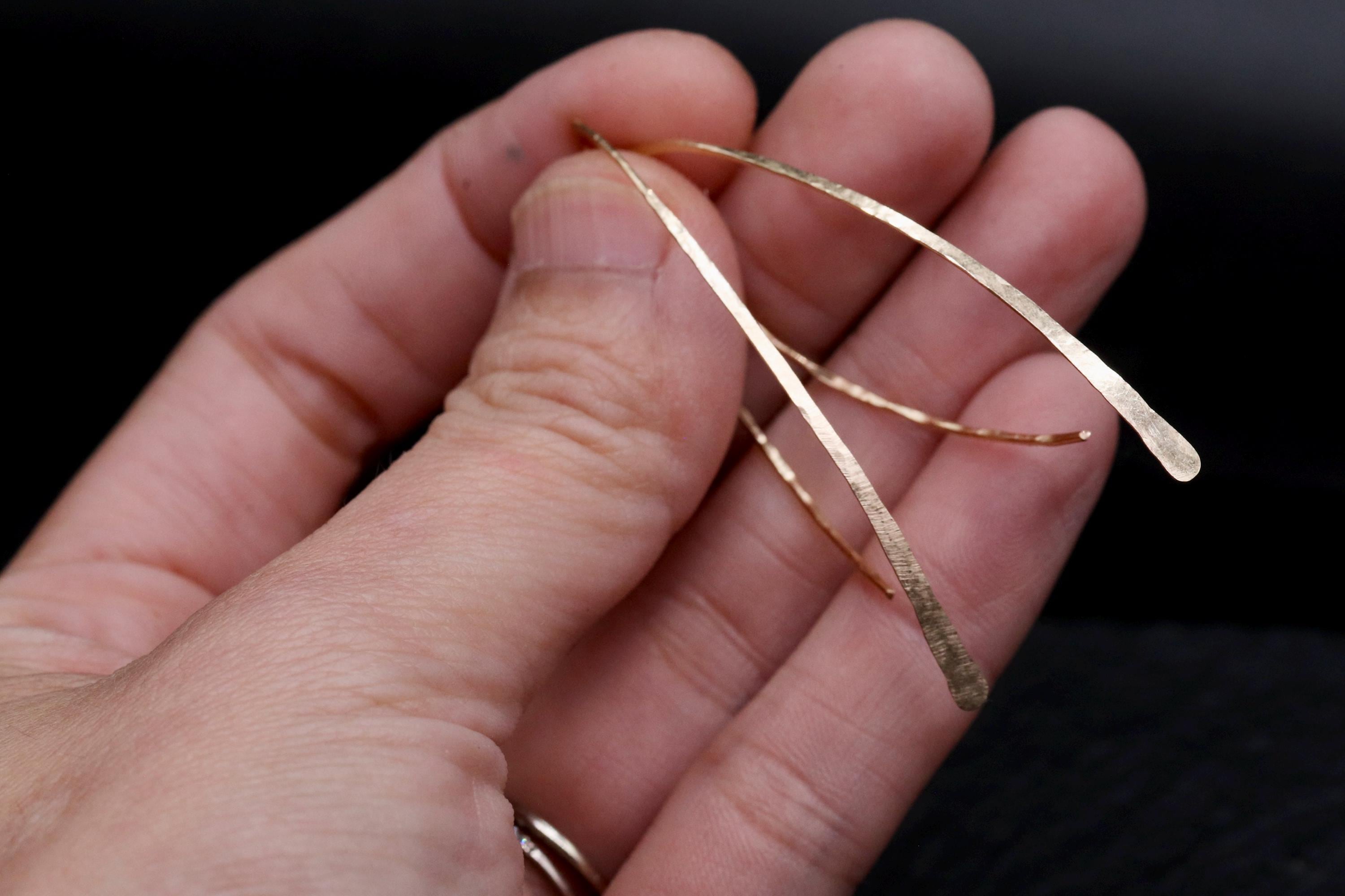 A close-up image of a person's hand holding a gold-colored metal object, possibly a piece of jewelry or a decorative item.