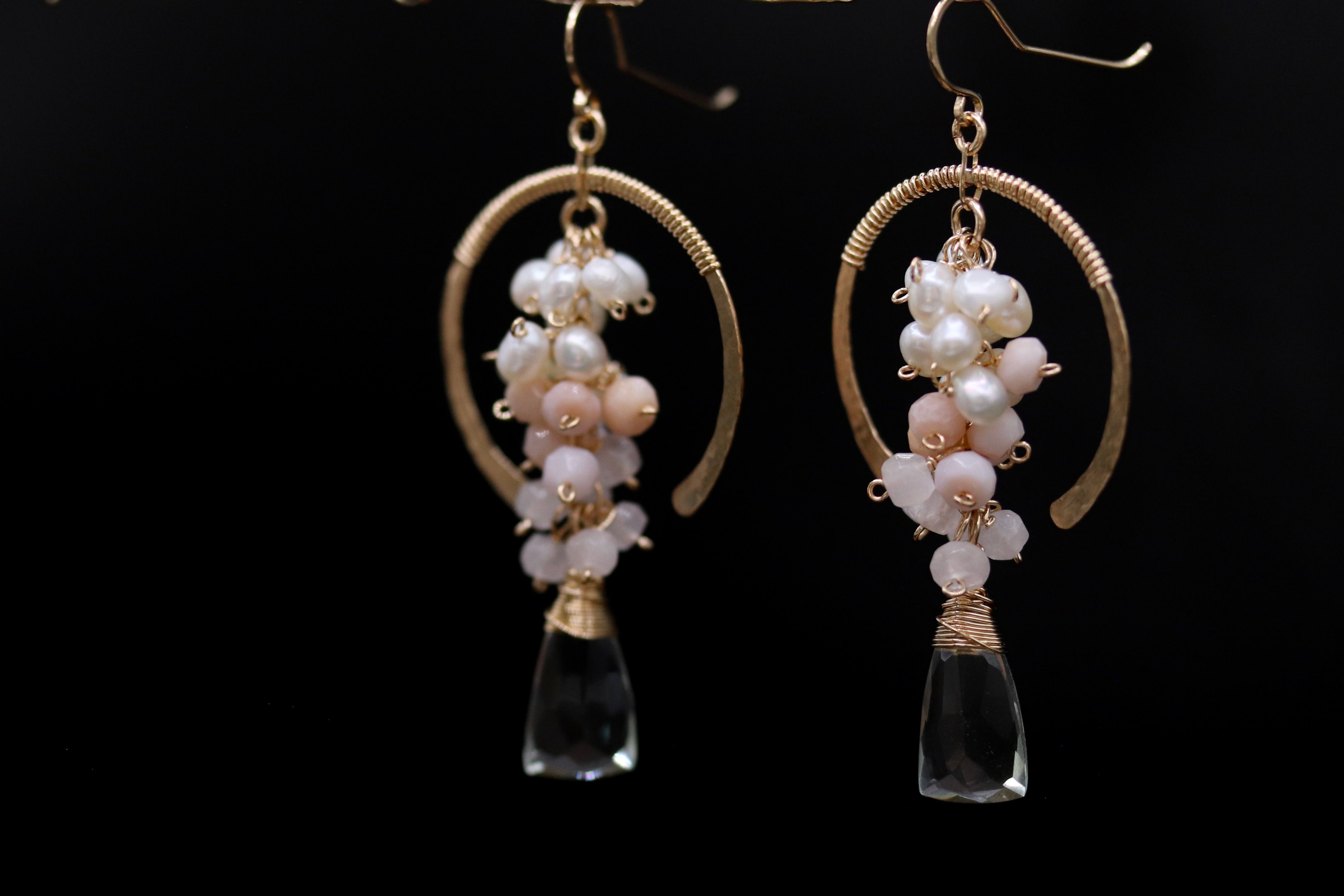 A pair of elegant earrings with clear gemstone accents and a cluster of white and pink pearls.