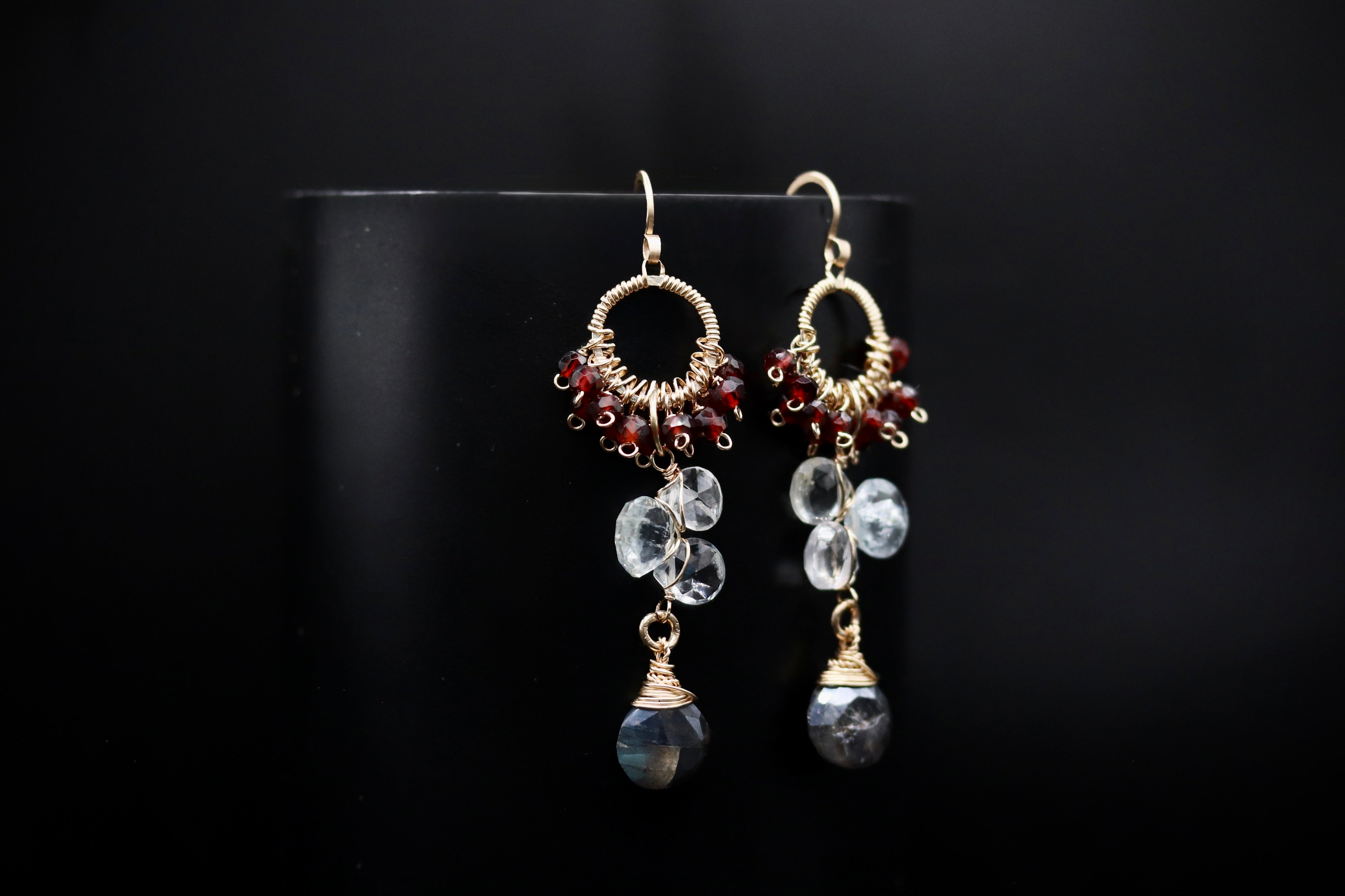 A pair of elegant earrings with clear gemstone accents and gold-colored metalwork, displayed against a black background.