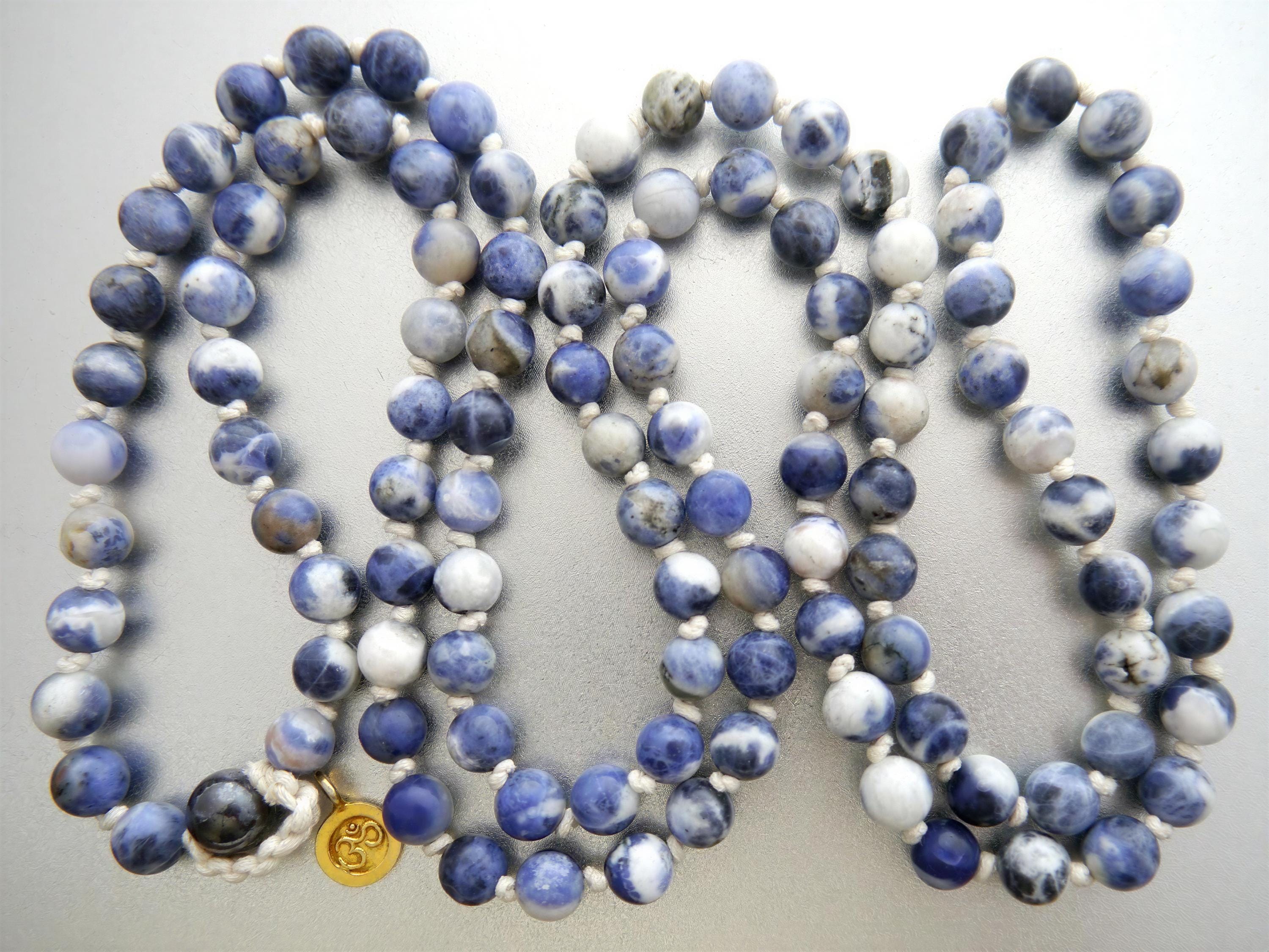 a collection of blue and white beads arranged in a decorative manner, with a gold-colored bead clasp visible.