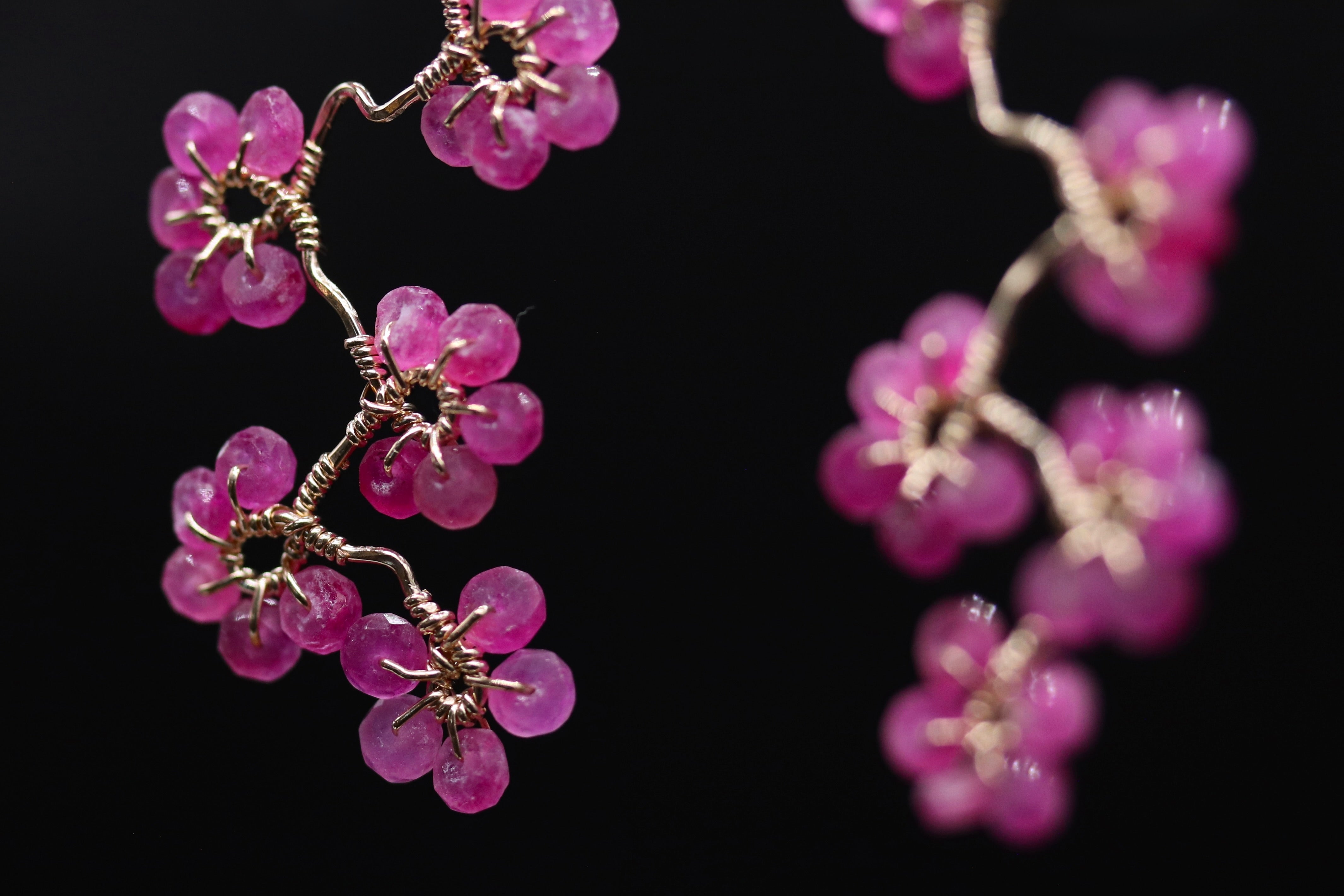 A close-up view of a delicate wire sculpture adorned with small, round, pink beads that resemble flowers.