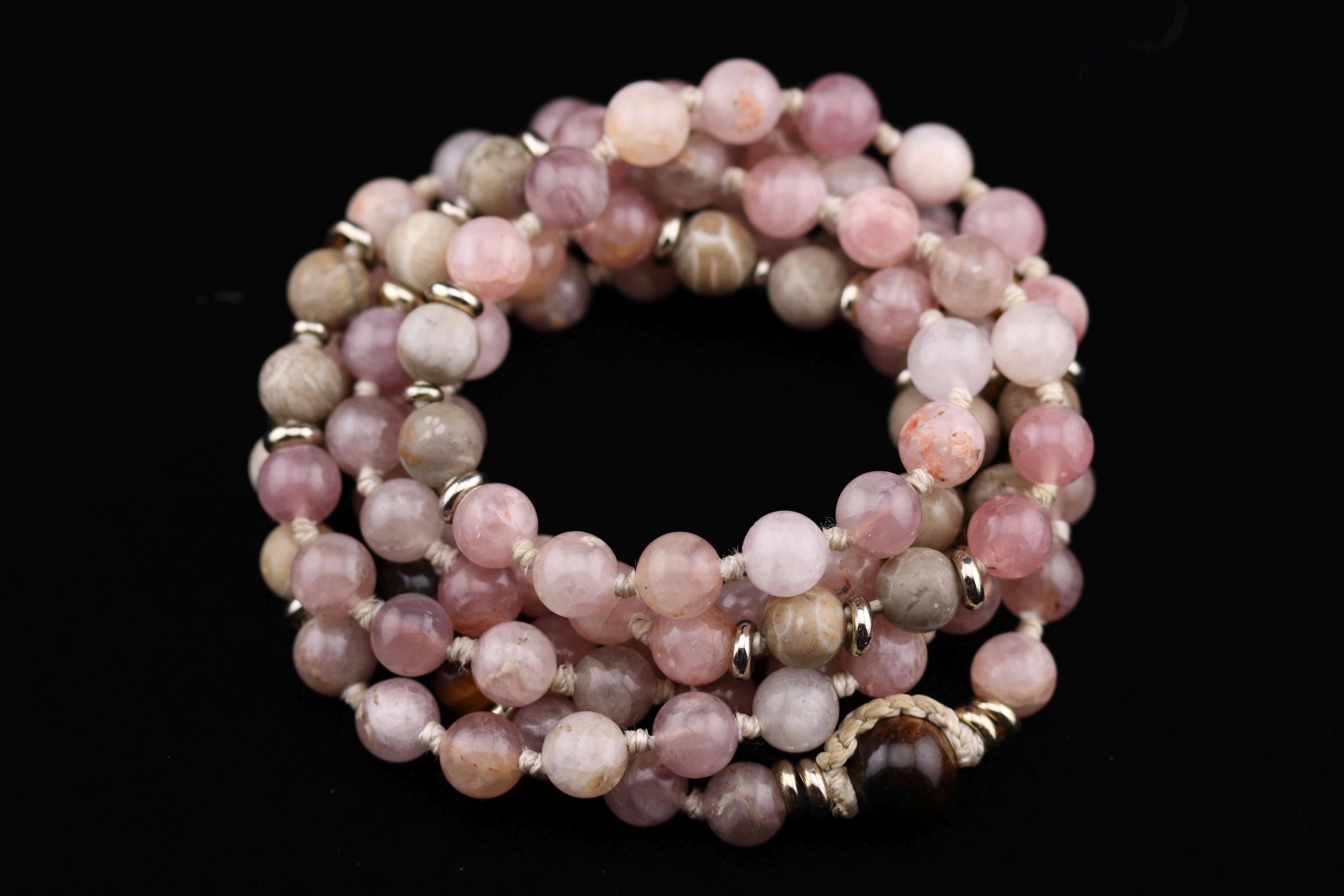 A beaded bracelet with a variety of colors, including shades of pink, gray, and brown, arranged in a circular pattern against a black background.