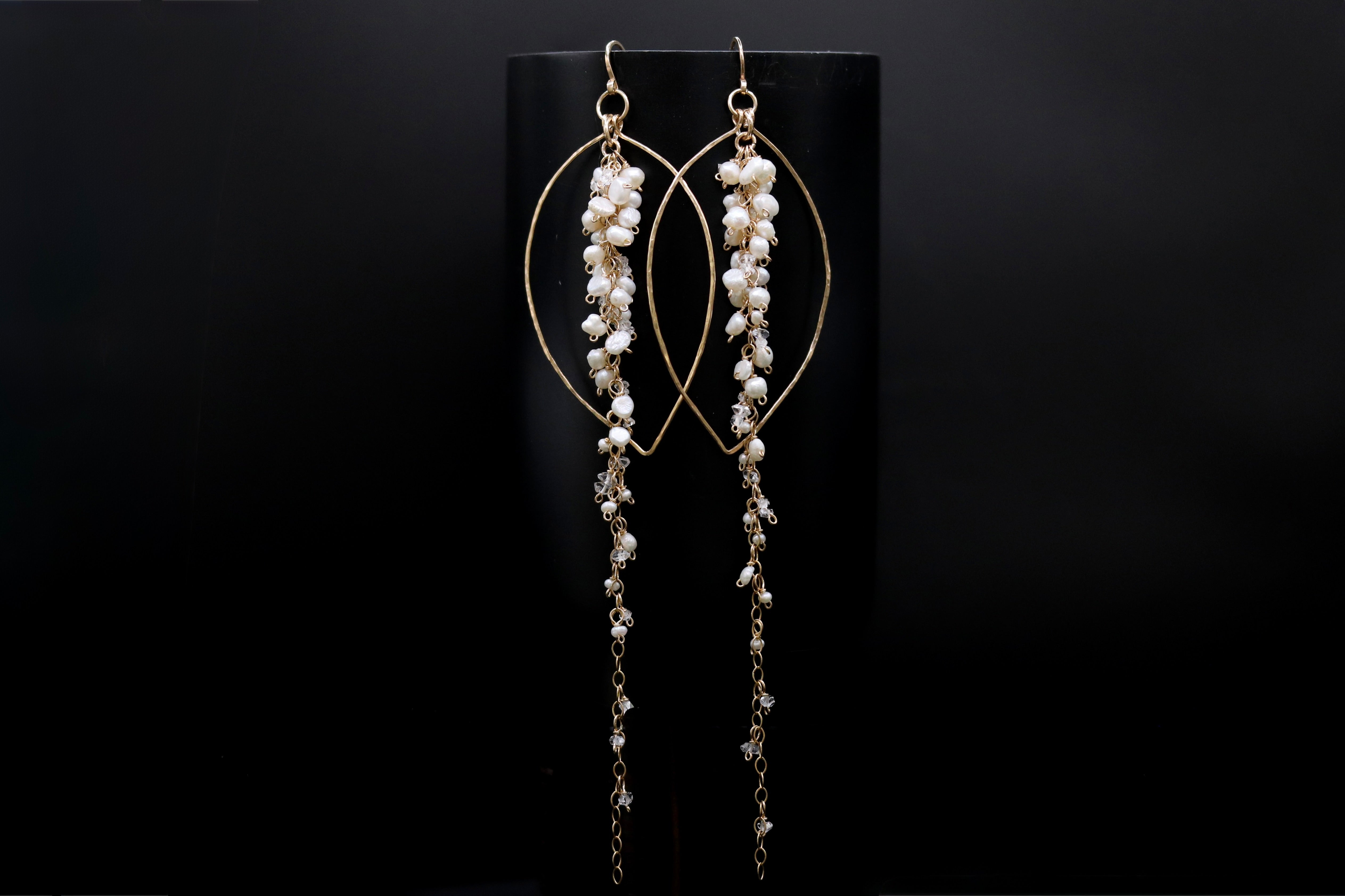 A pair of elegant gold earrings with long, dangling chains and small white pearls or beads.