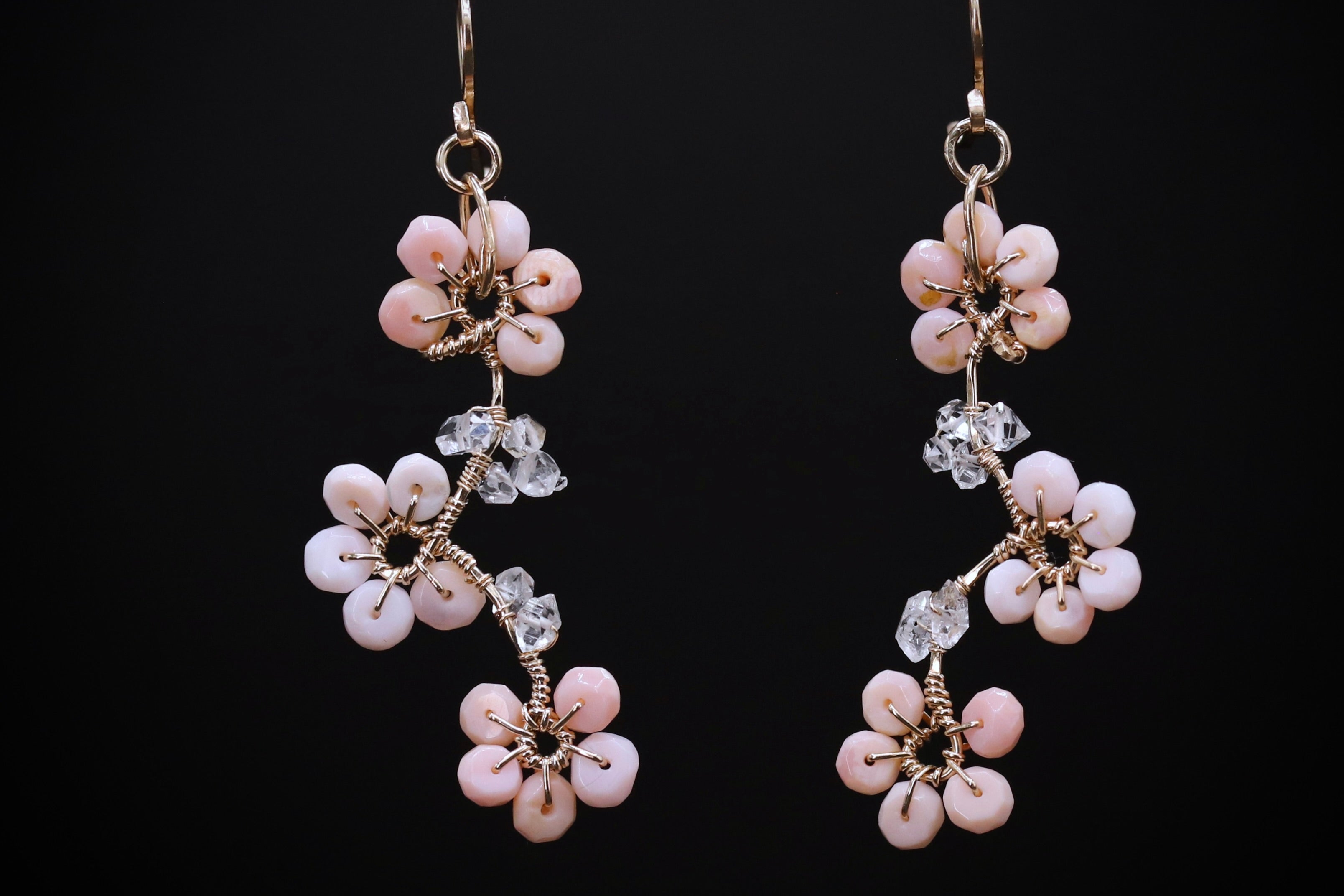 A pair of delicate earrings with a floral design, featuring small white flowers and clear gemstones.