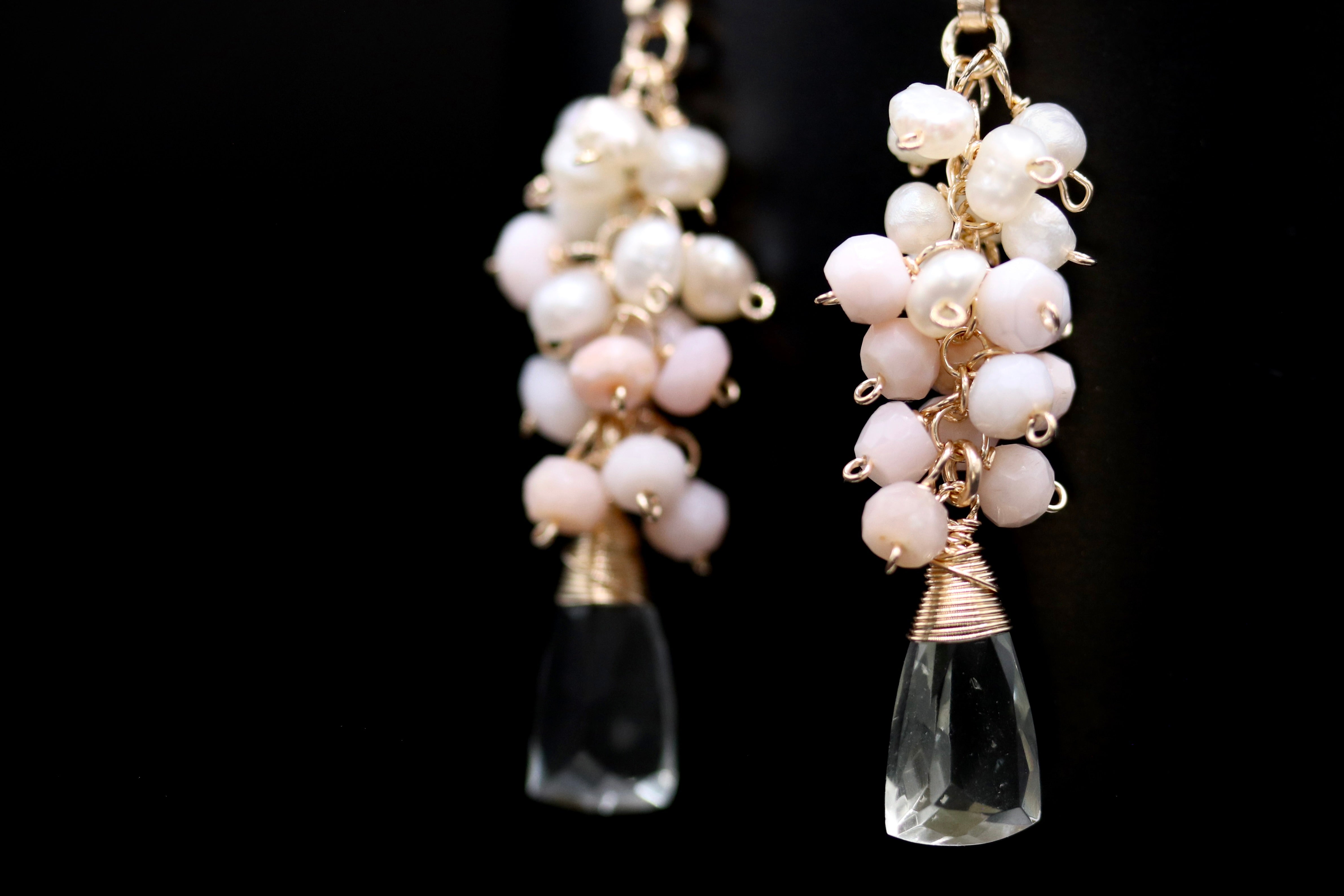 A pair of elegant earrings with clear crystal pendants and white pearl beads hanging from the ends.