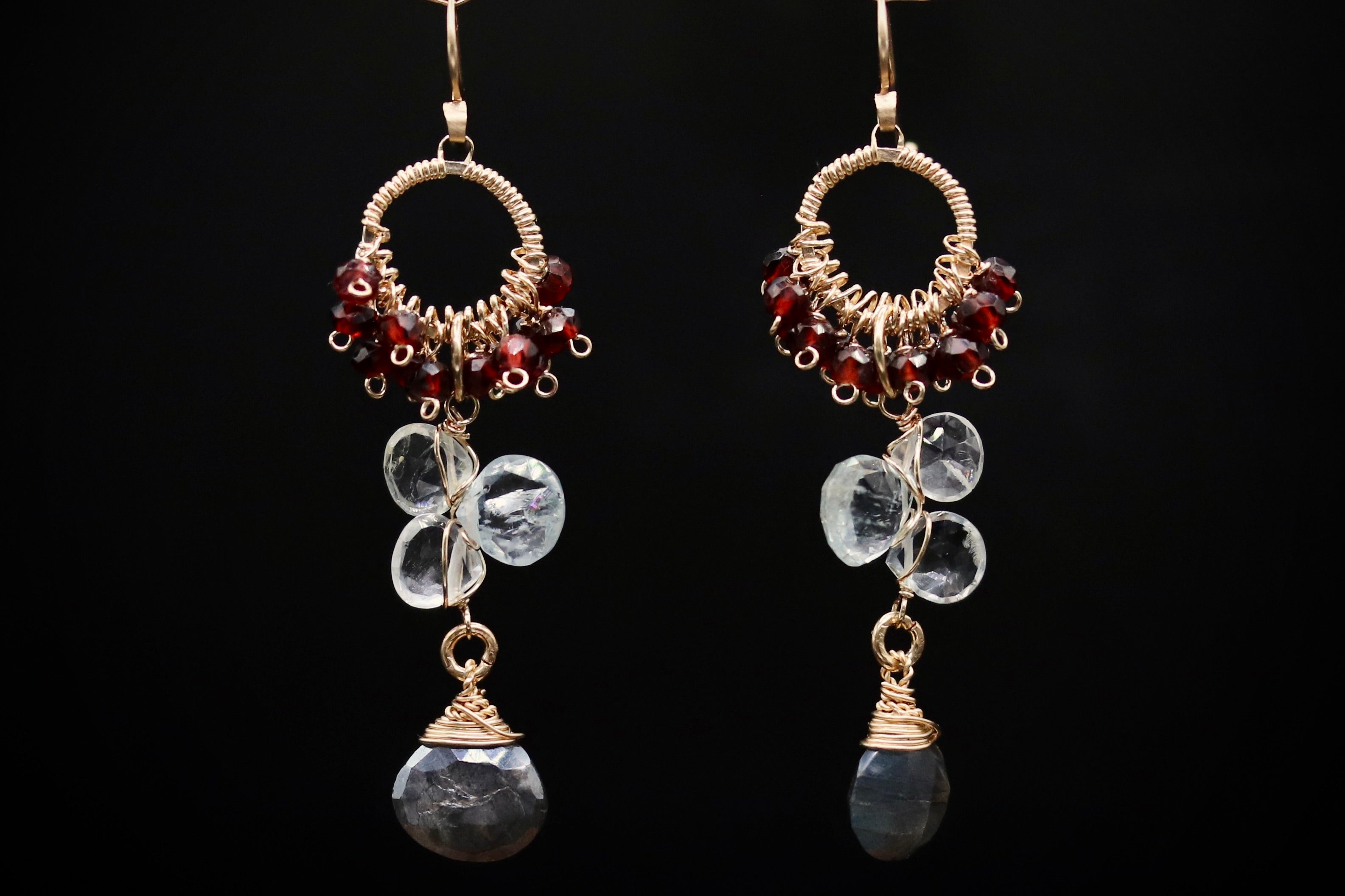 A pair of elegant earrings with clear gemstone accents and metal wire elements, set against a black background.