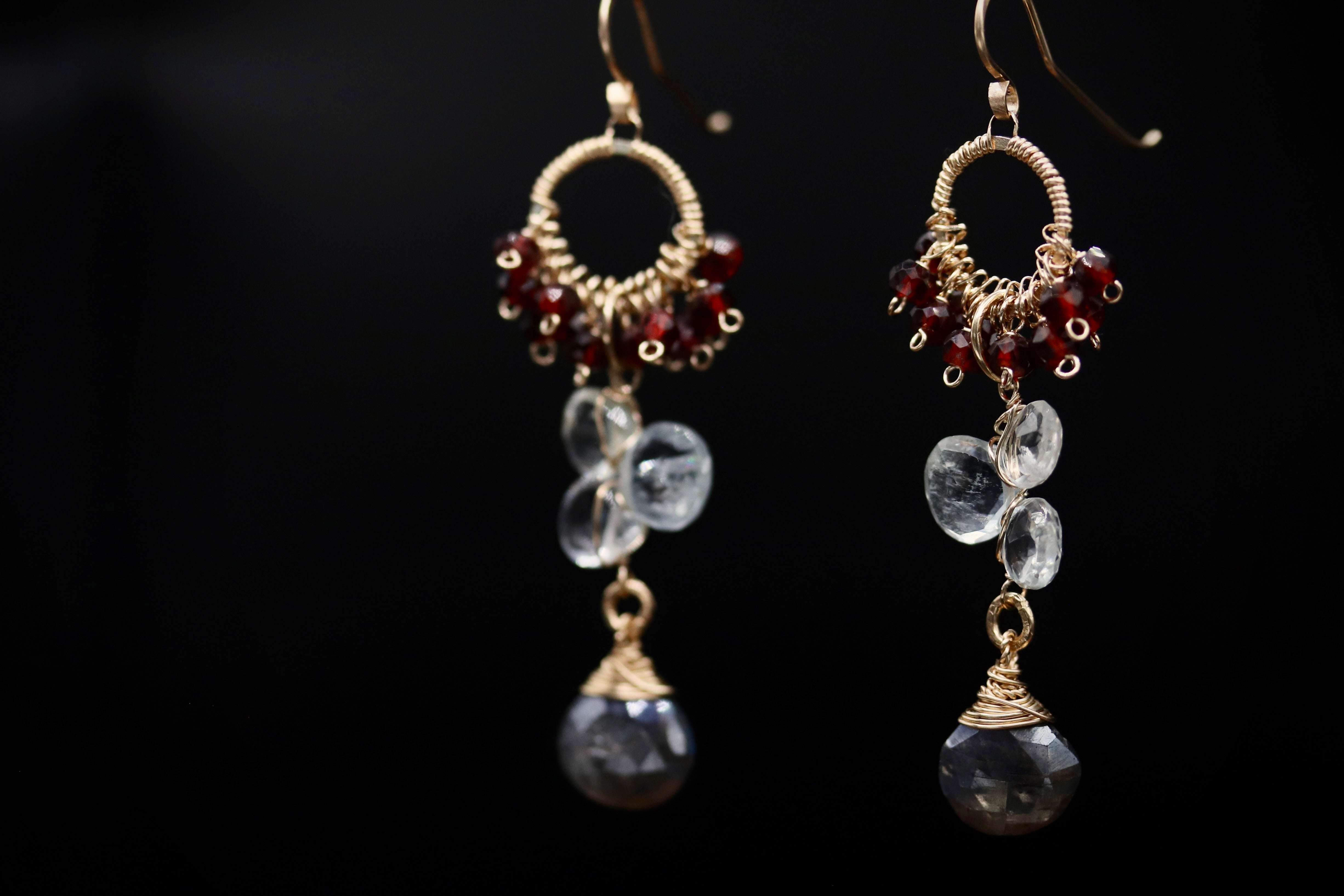 A pair of elegant earrings with clear gemstone accents and metal wire elements, set against a dark background.