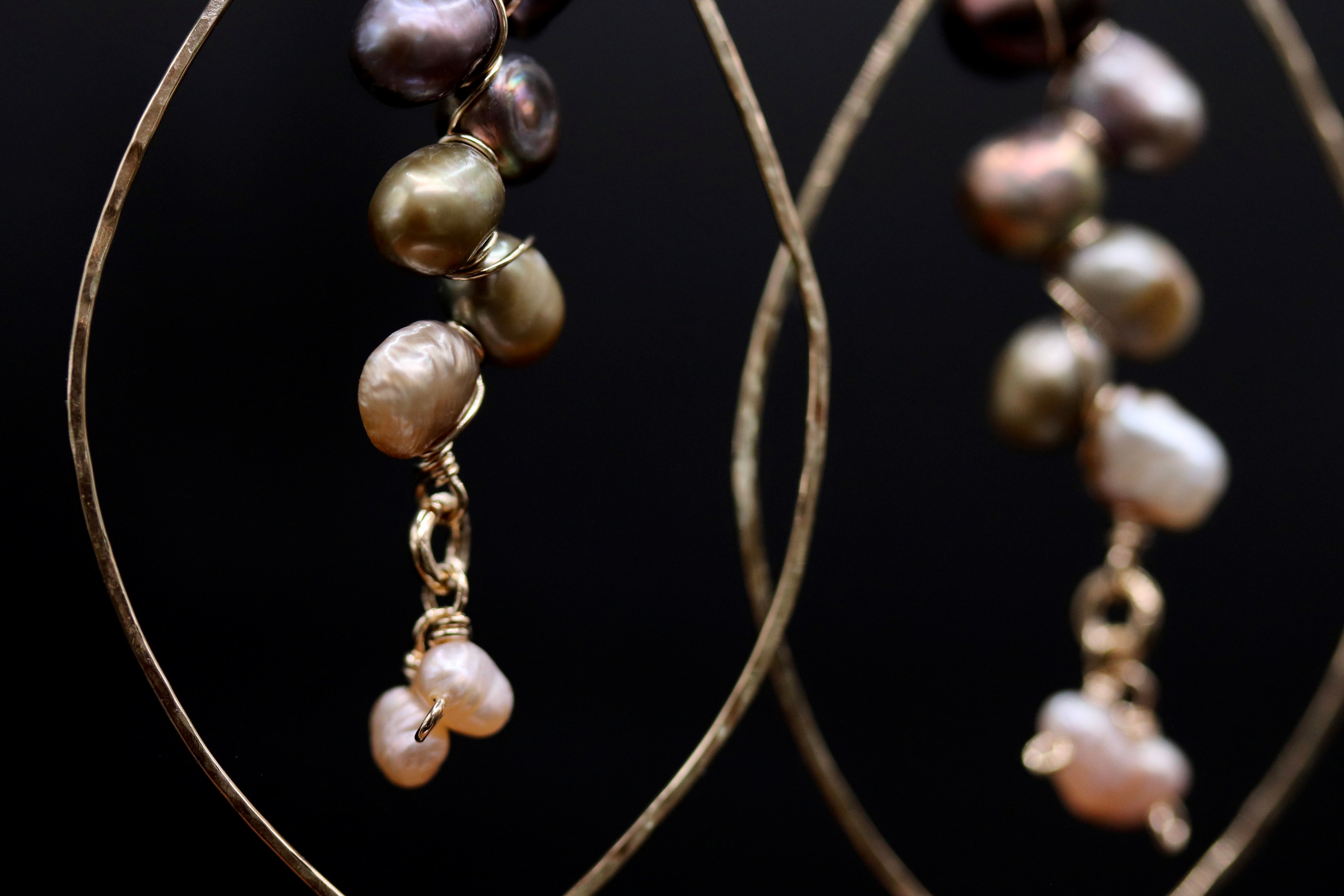 A close-up view of a pair of earrings with multiple strands of pearls and gold-colored metal.