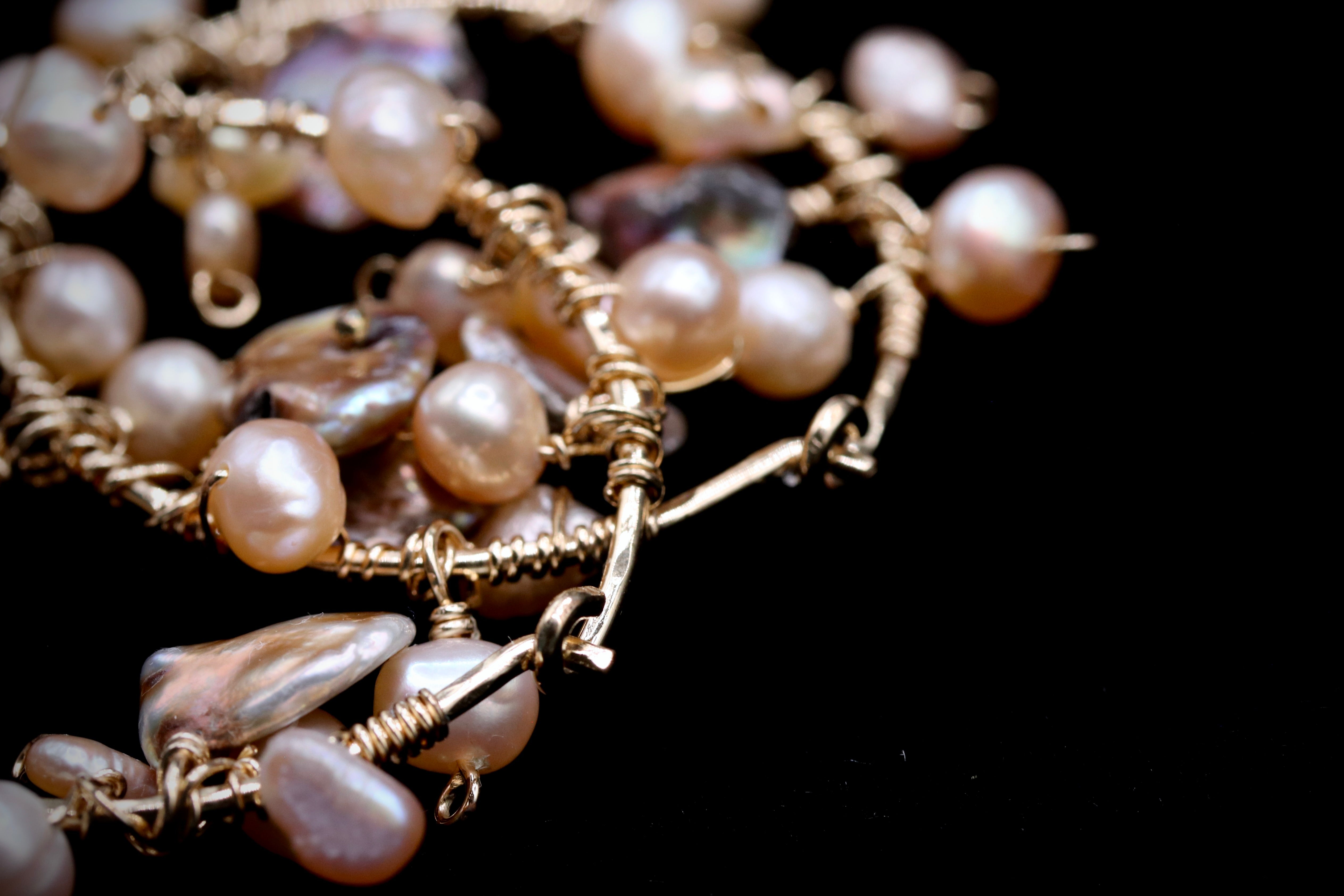 A close-up view of a delicate necklace made of small, round, white pearls strung together with a metallic wire.