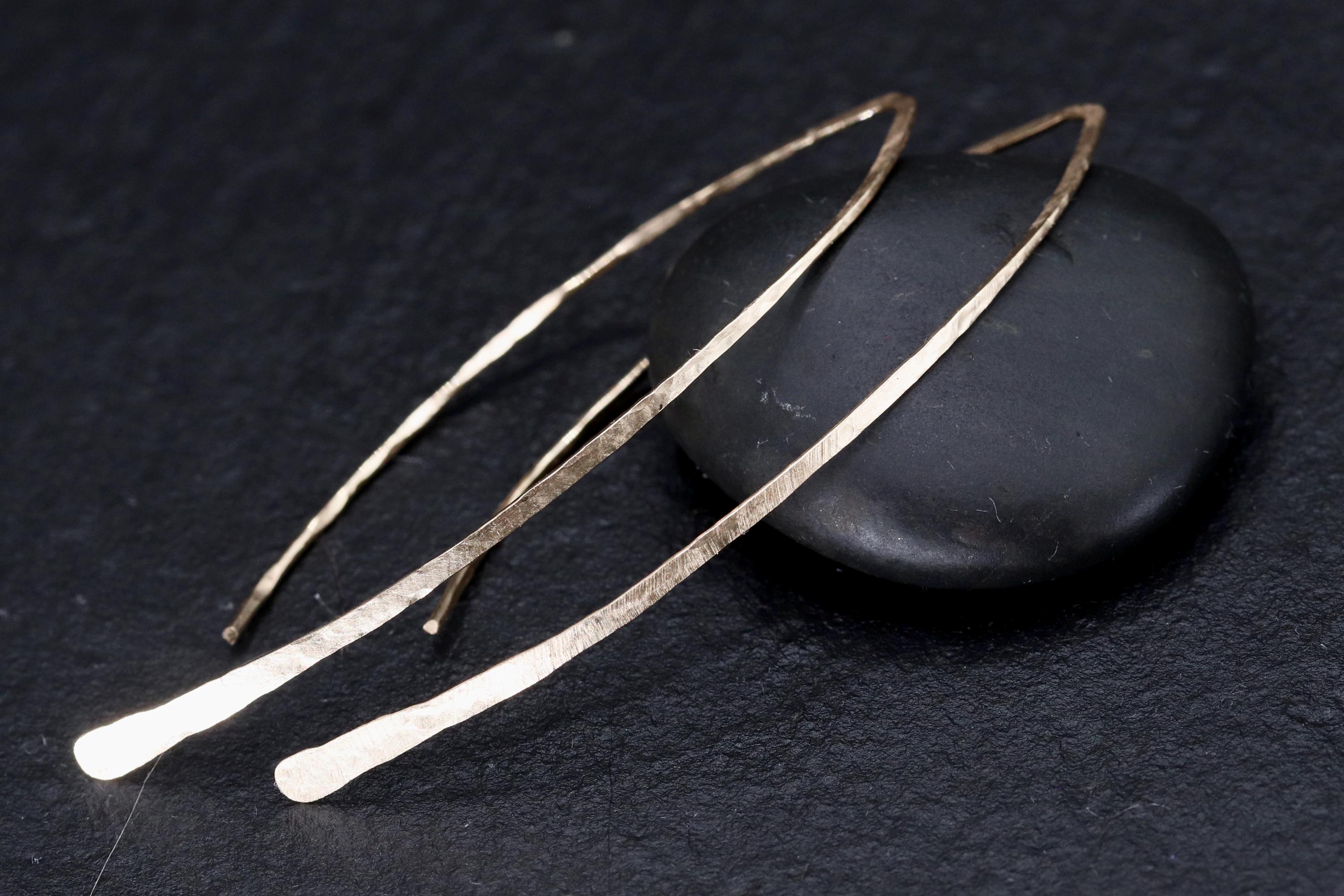 a pair of gold earrings with a dark background.