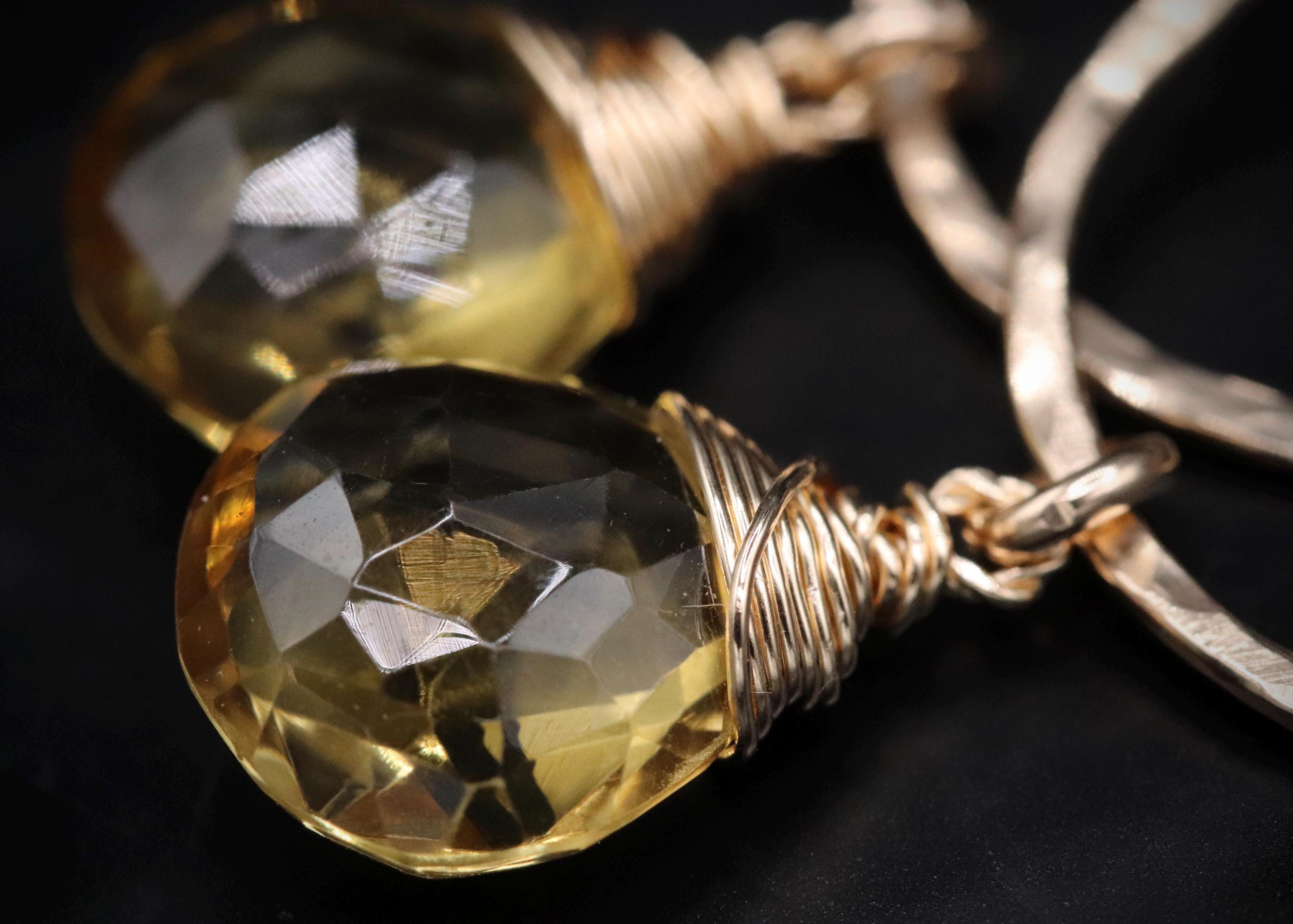 A close-up image of a pair of earrings with a yellow gemstone and a twisted metal wire.