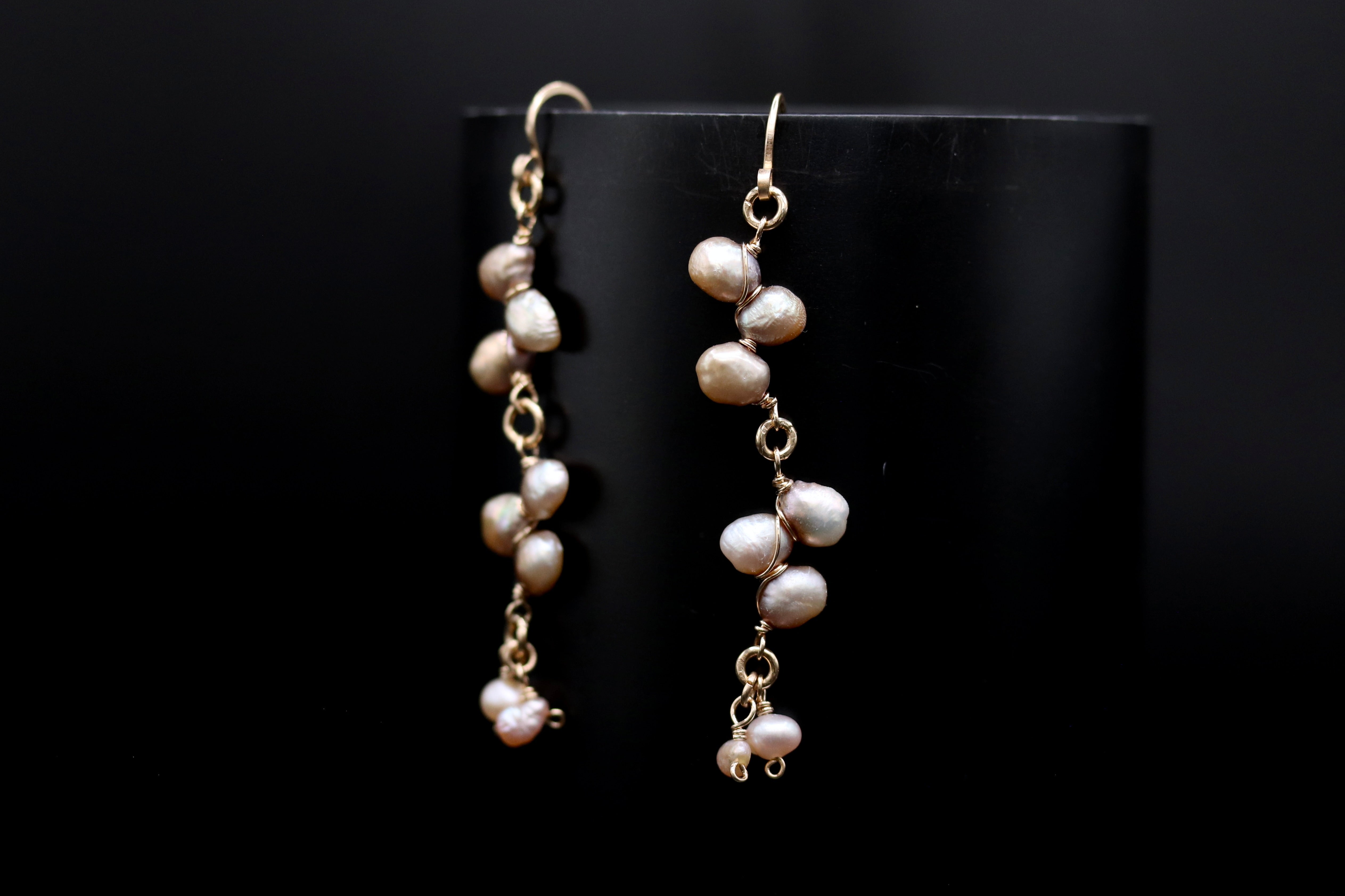 A pair of elegant earrings with a delicate design, featuring a row of small pearls hanging from a gold chain.