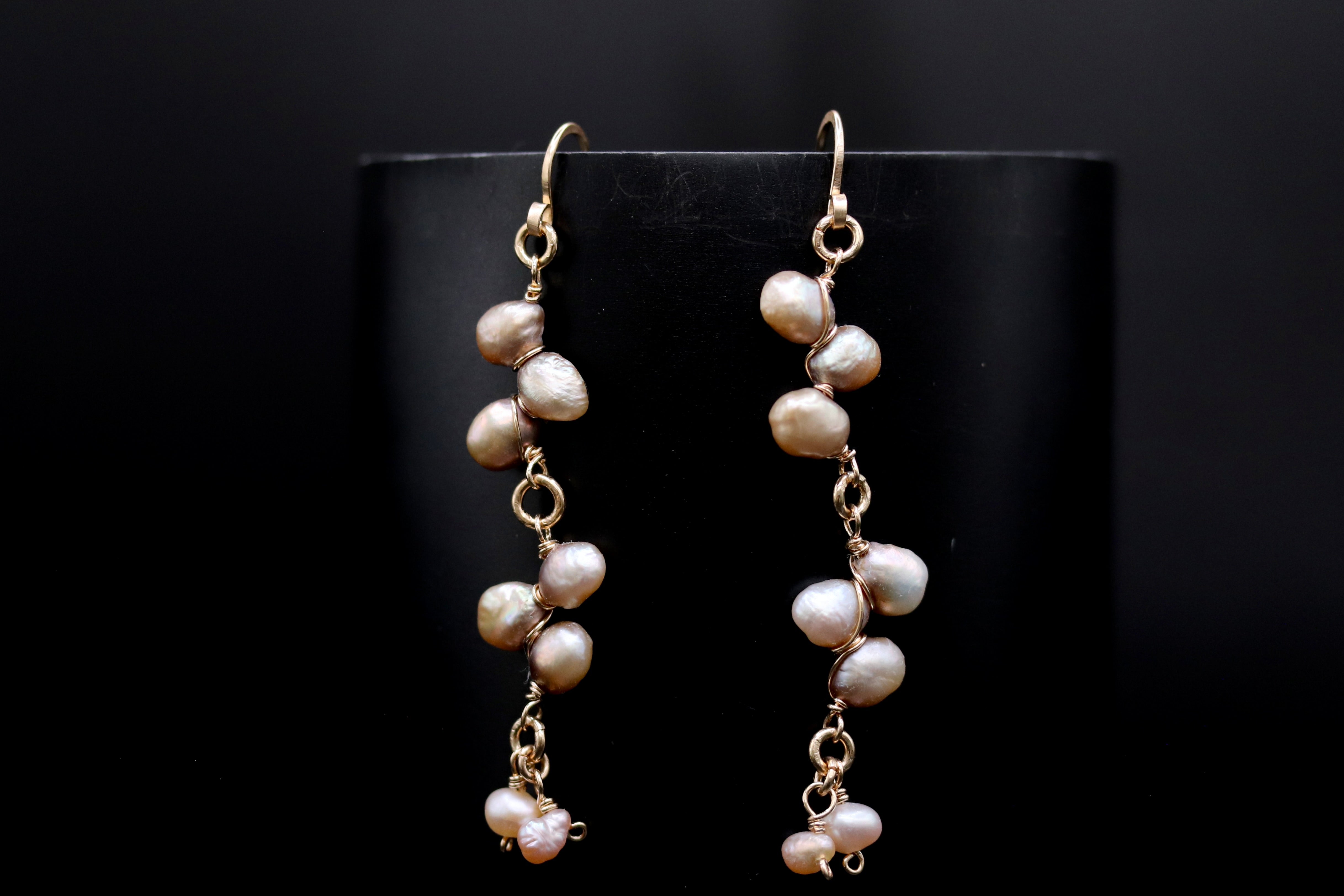 A pair of elegant earrings with a delicate design, featuring a cluster of small pearls hanging from a thin gold chain.