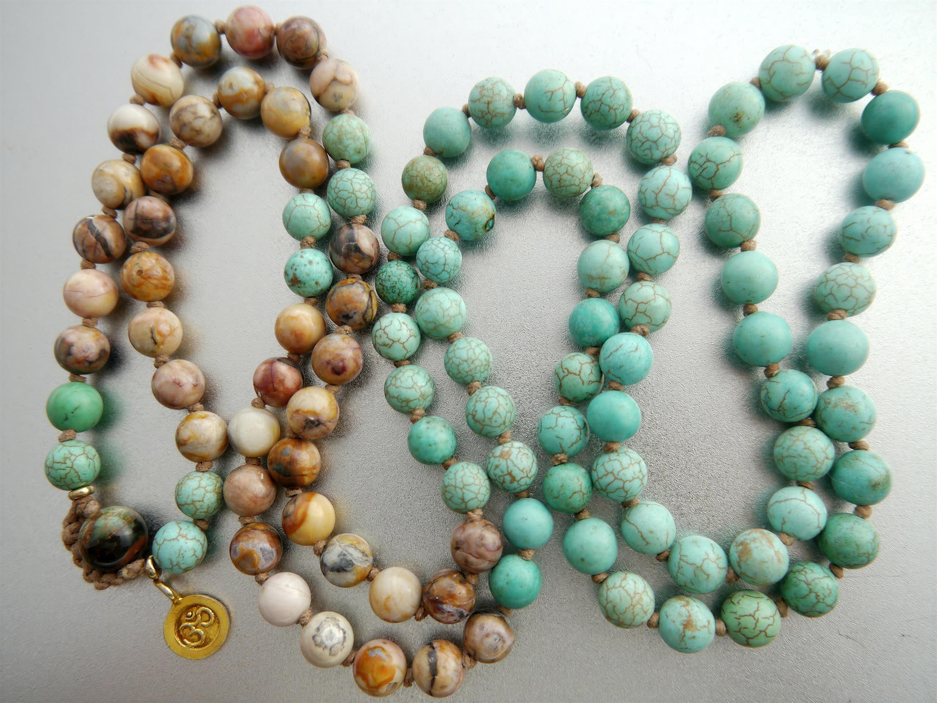 a collection of necklaces with various colored beads, including turquoise, brown, and white beads, arranged in a row.