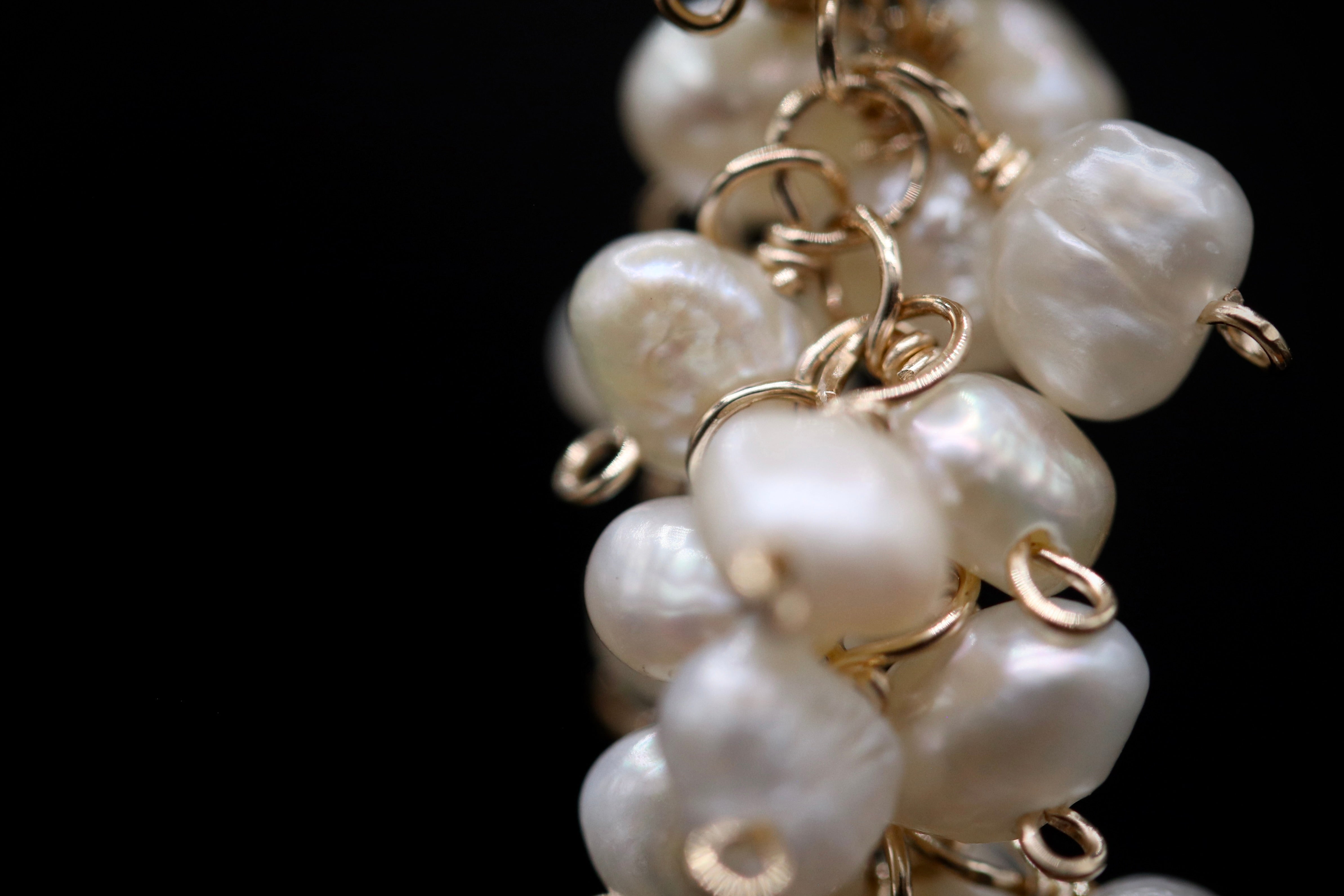 A close-up view of a delicate chain of white pearls with gold-colored metal links, creating an elegant and intricate design.