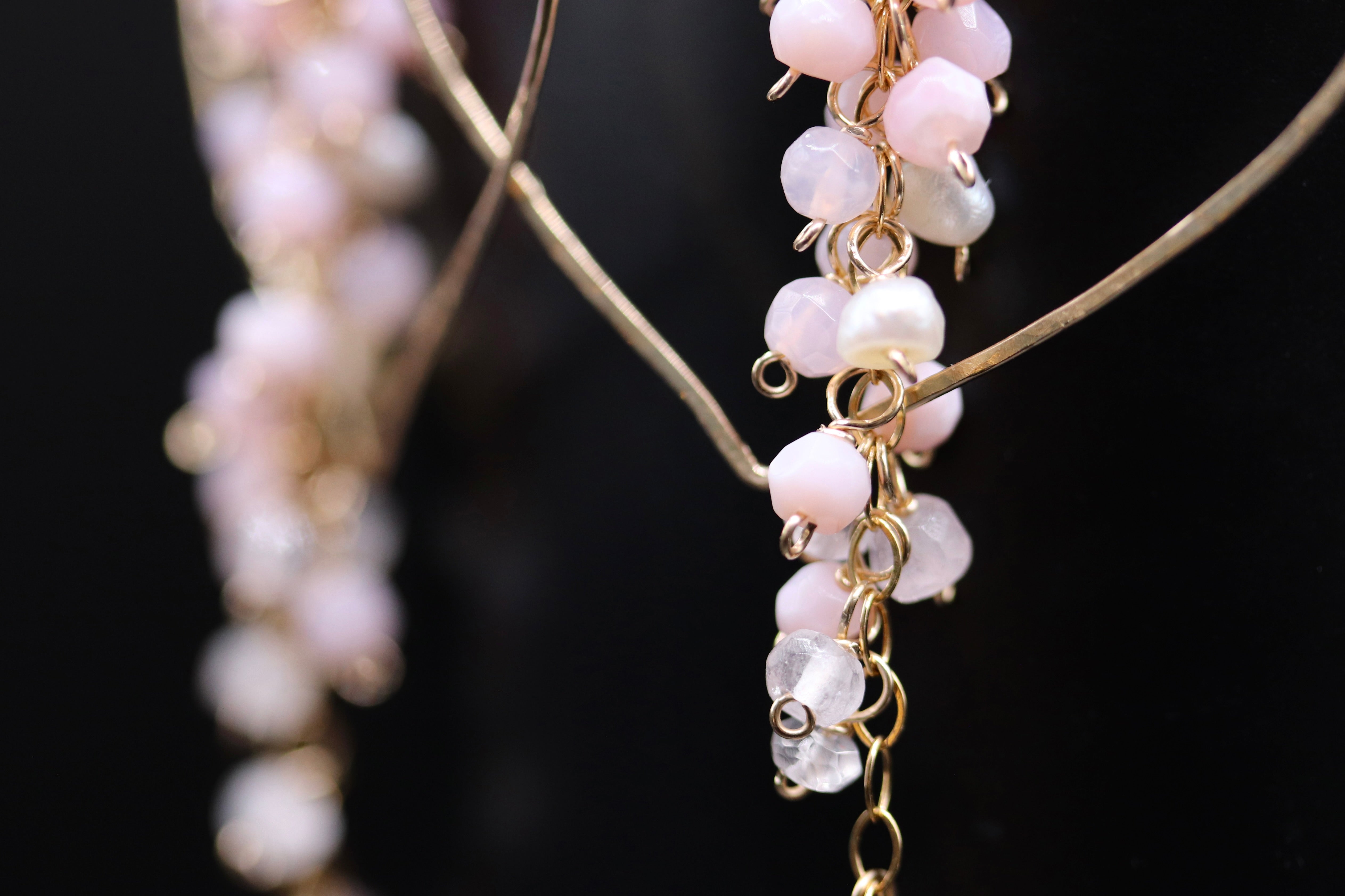 A close-up view of a delicate gold chain with dangling white and clear gemstone earrings.