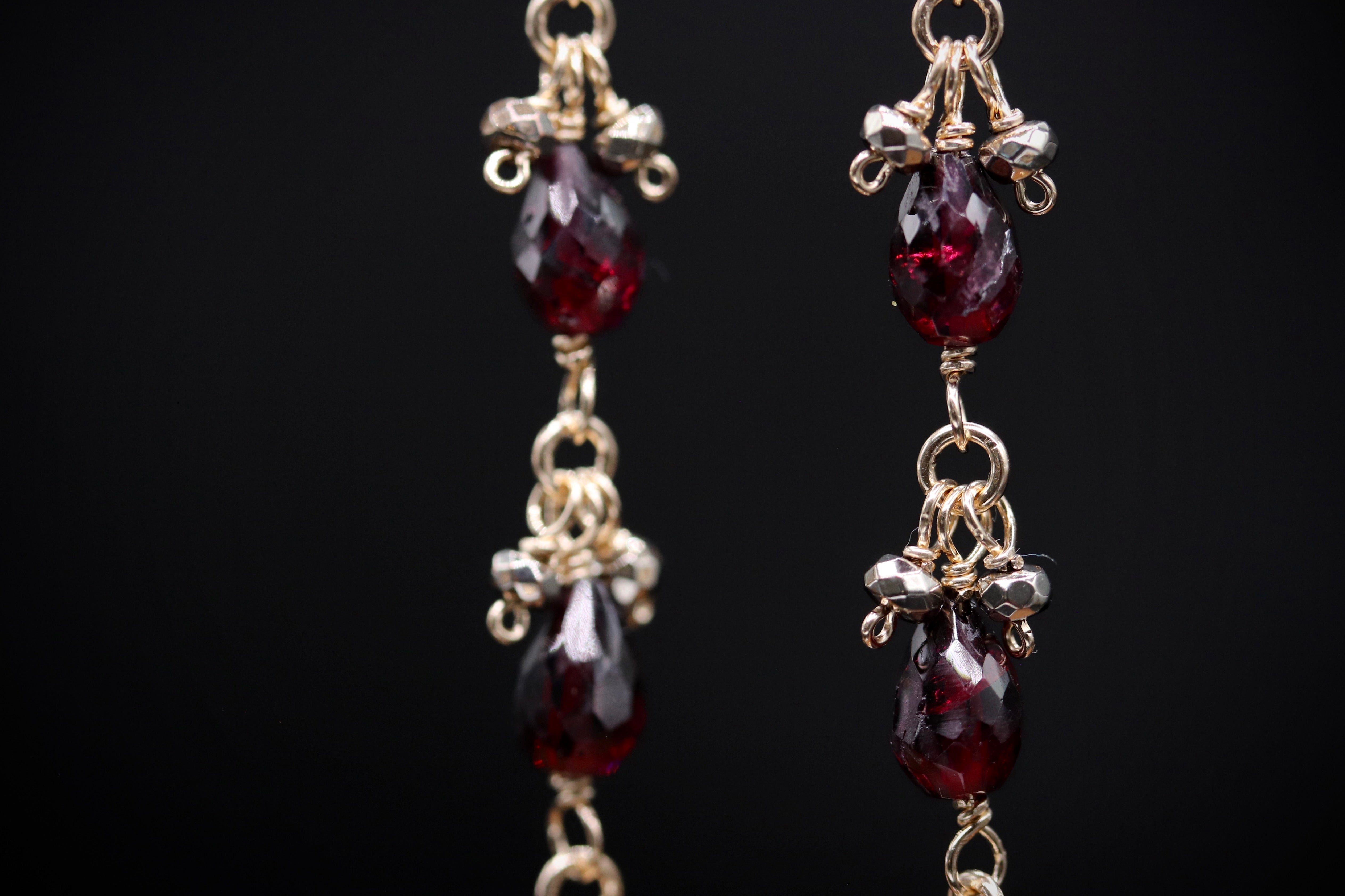 A close-up view of a pair of earrings with red gemstones and intricate metalwork.