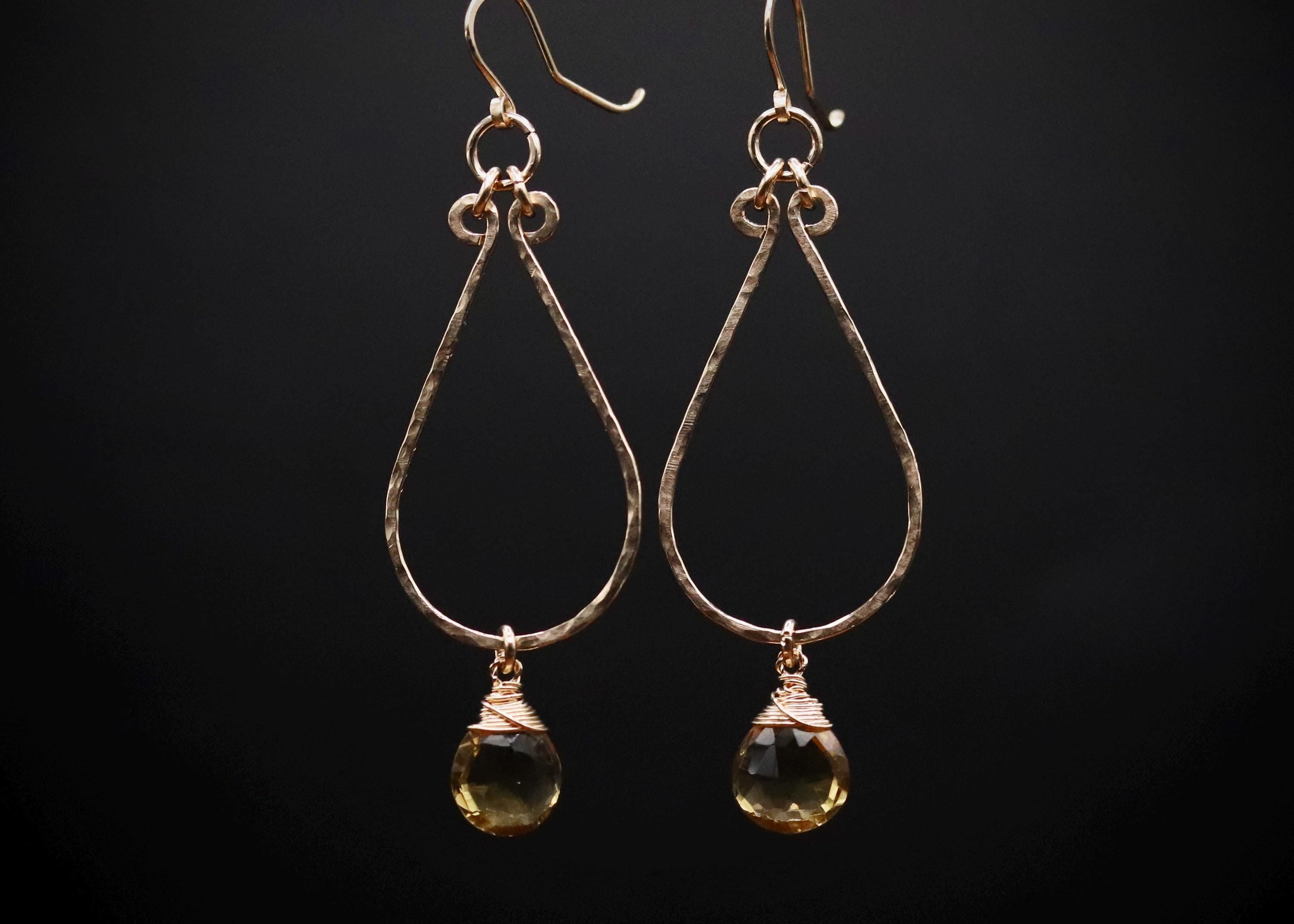 A pair of gold earrings with a clear gemstone dangling from each ear hook.