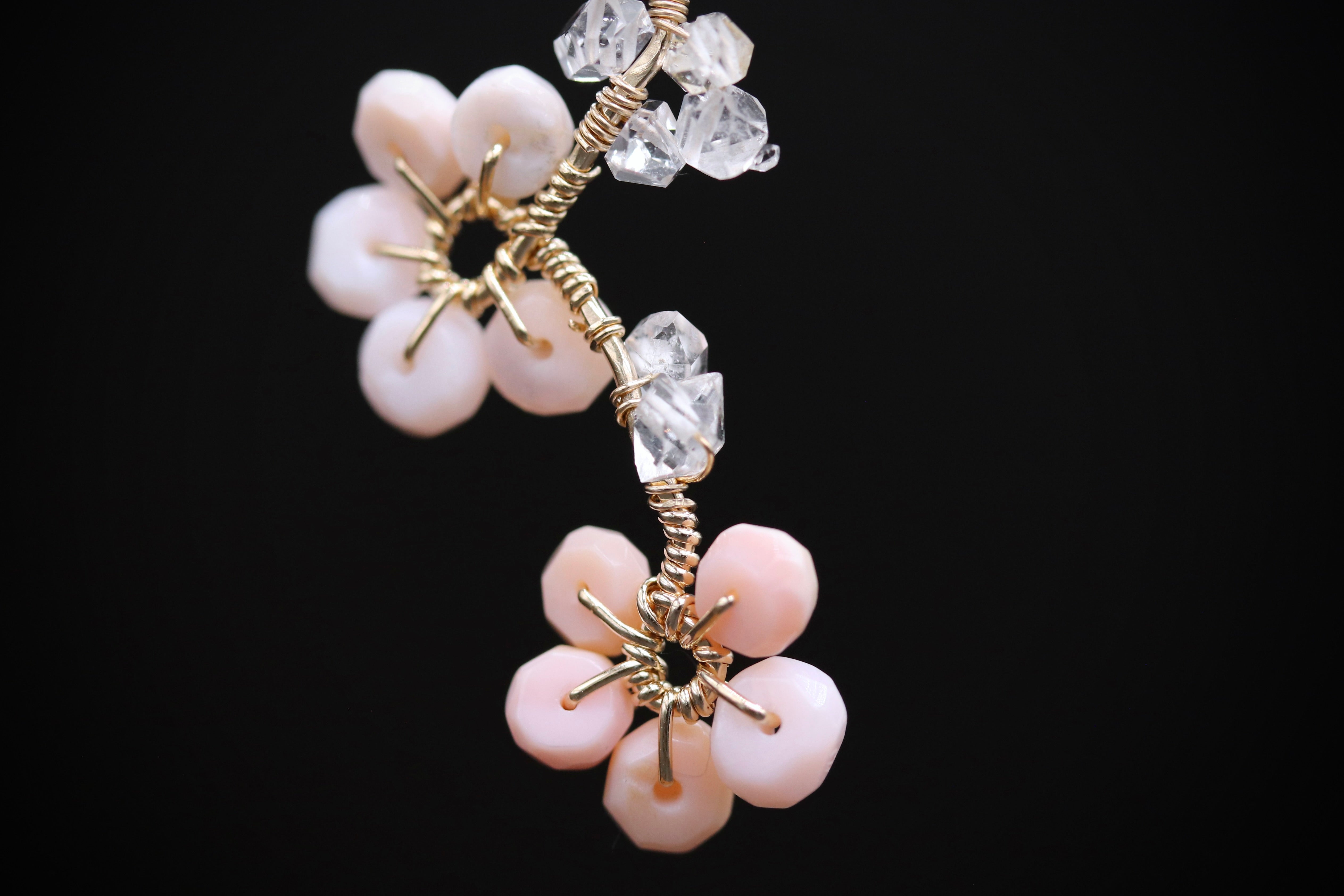 A close-up view of a delicate necklace with a combination of small beads and clear gemstones, resembling a flower-like design.