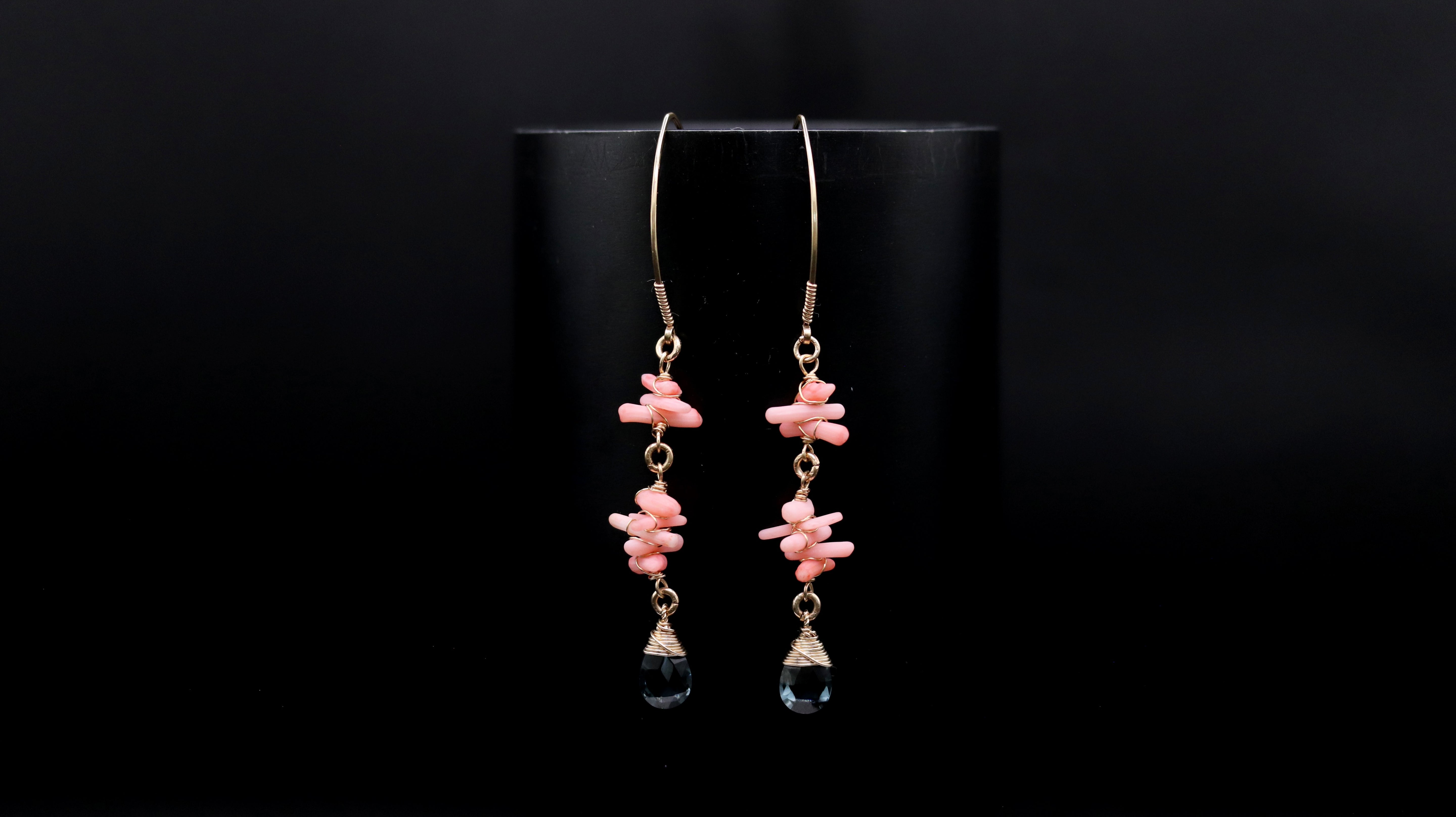 A pair of earrings with a black background and a pair of dangling earrings with pink and coral beads.