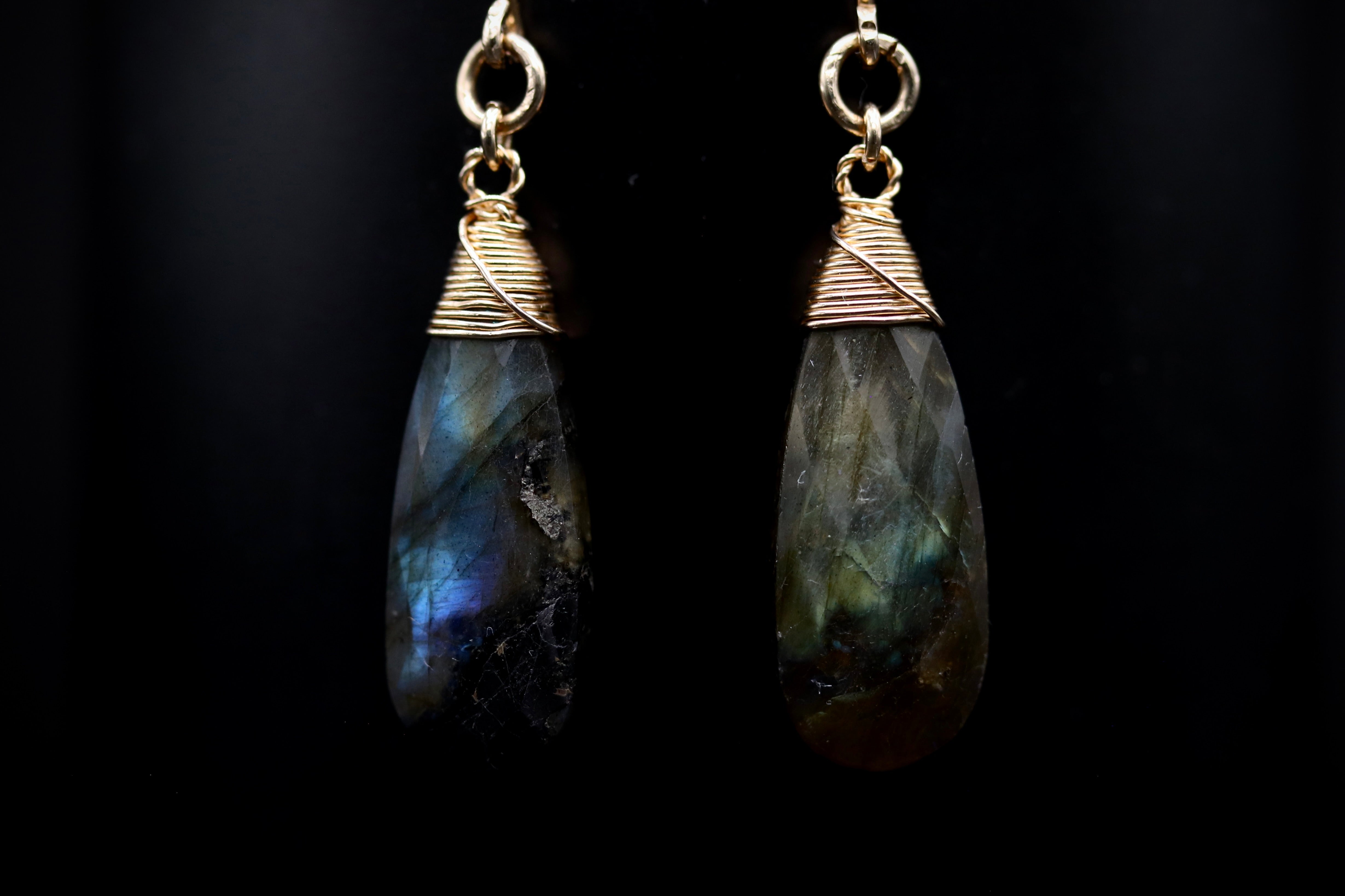 A pair of earrings with a dark stone pendant and a gold-colored metal clasp.