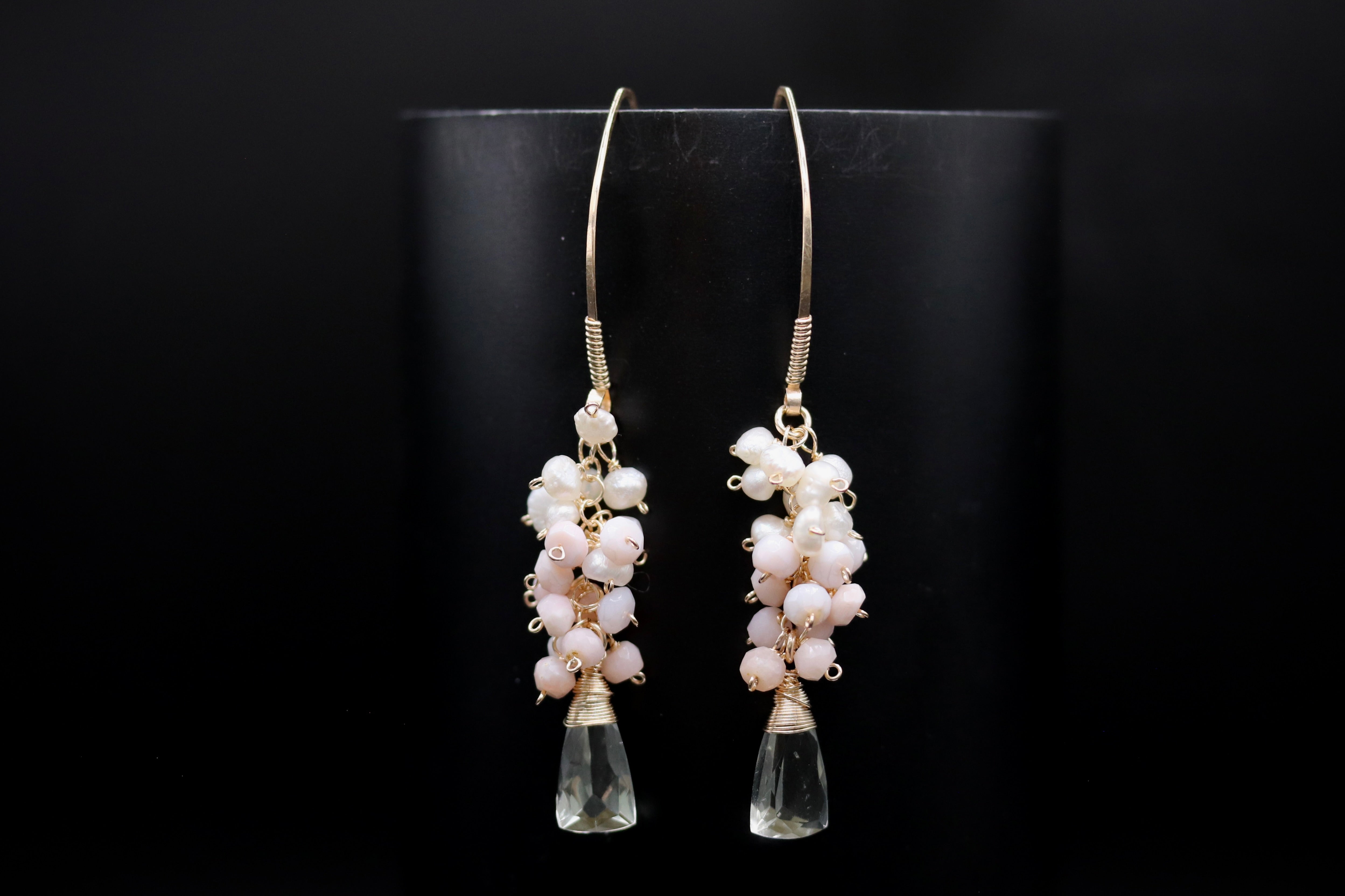 A pair of elegant earrings with clear gemstone accents and white pearl-like beads hanging from the bottom.