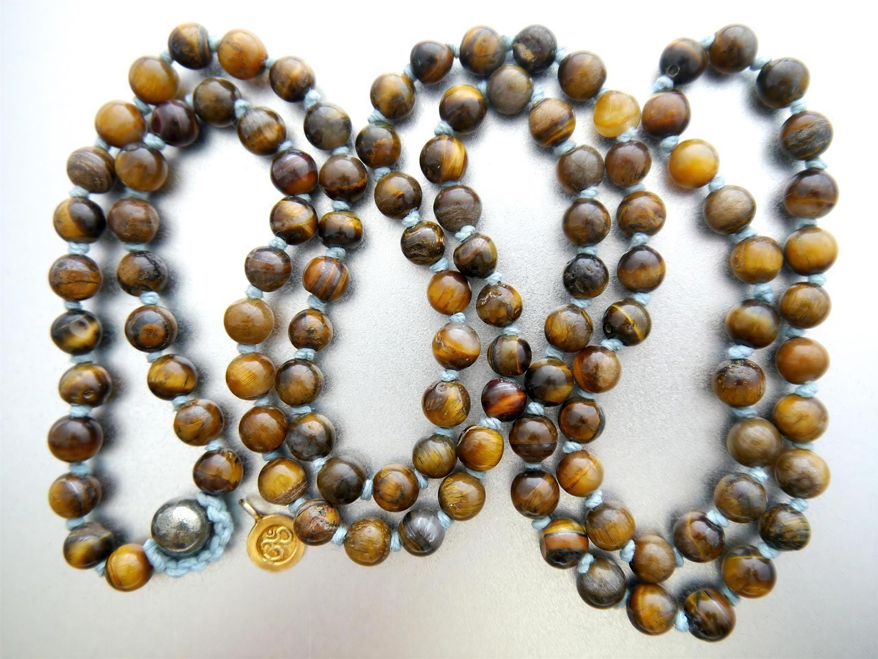 A necklace made of brown beads, possibly tiger or amber-colored, with a small gold pendant.