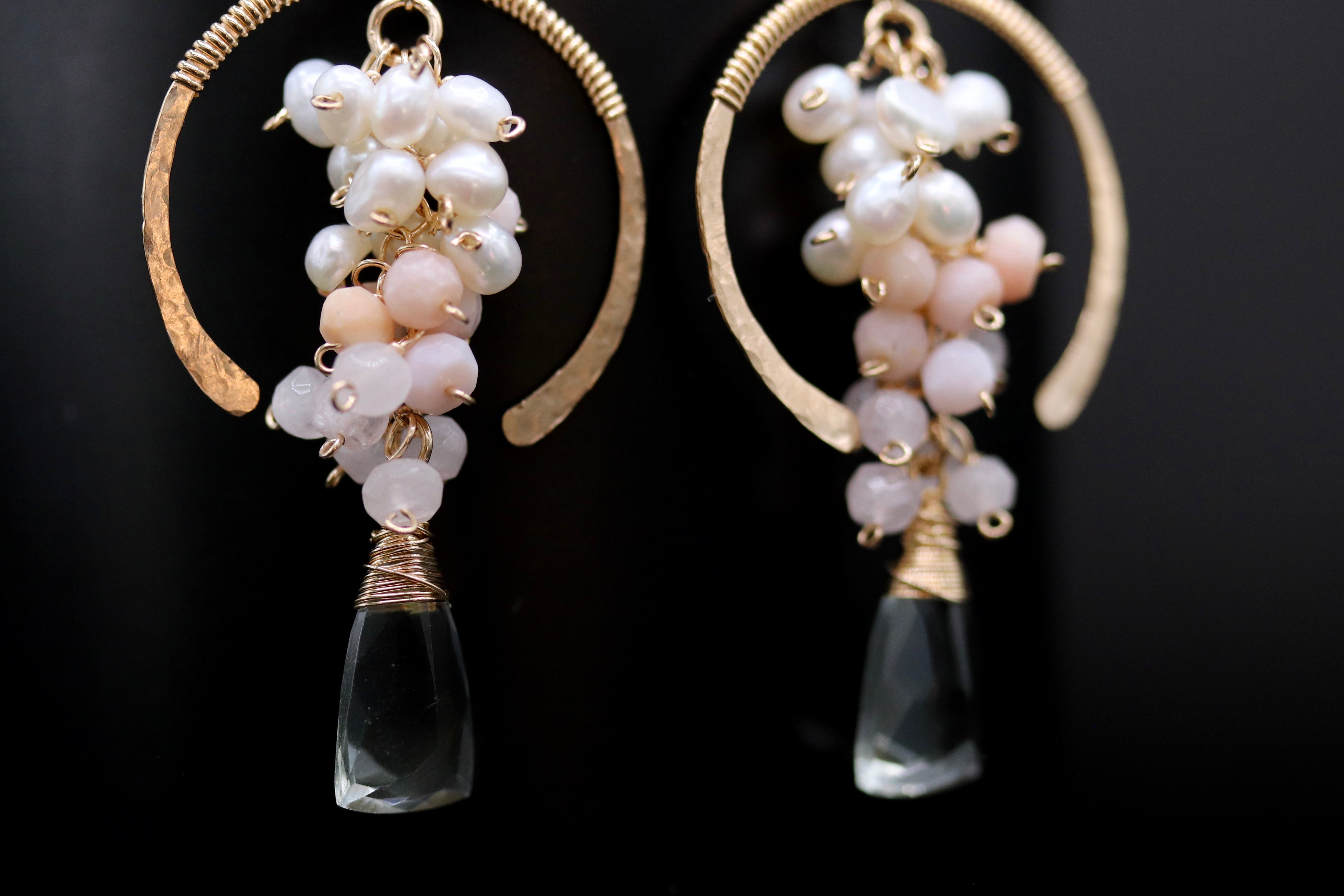 A pair of elegant earrings with clear gemstone pendants and white and pink beads hanging from the ends.