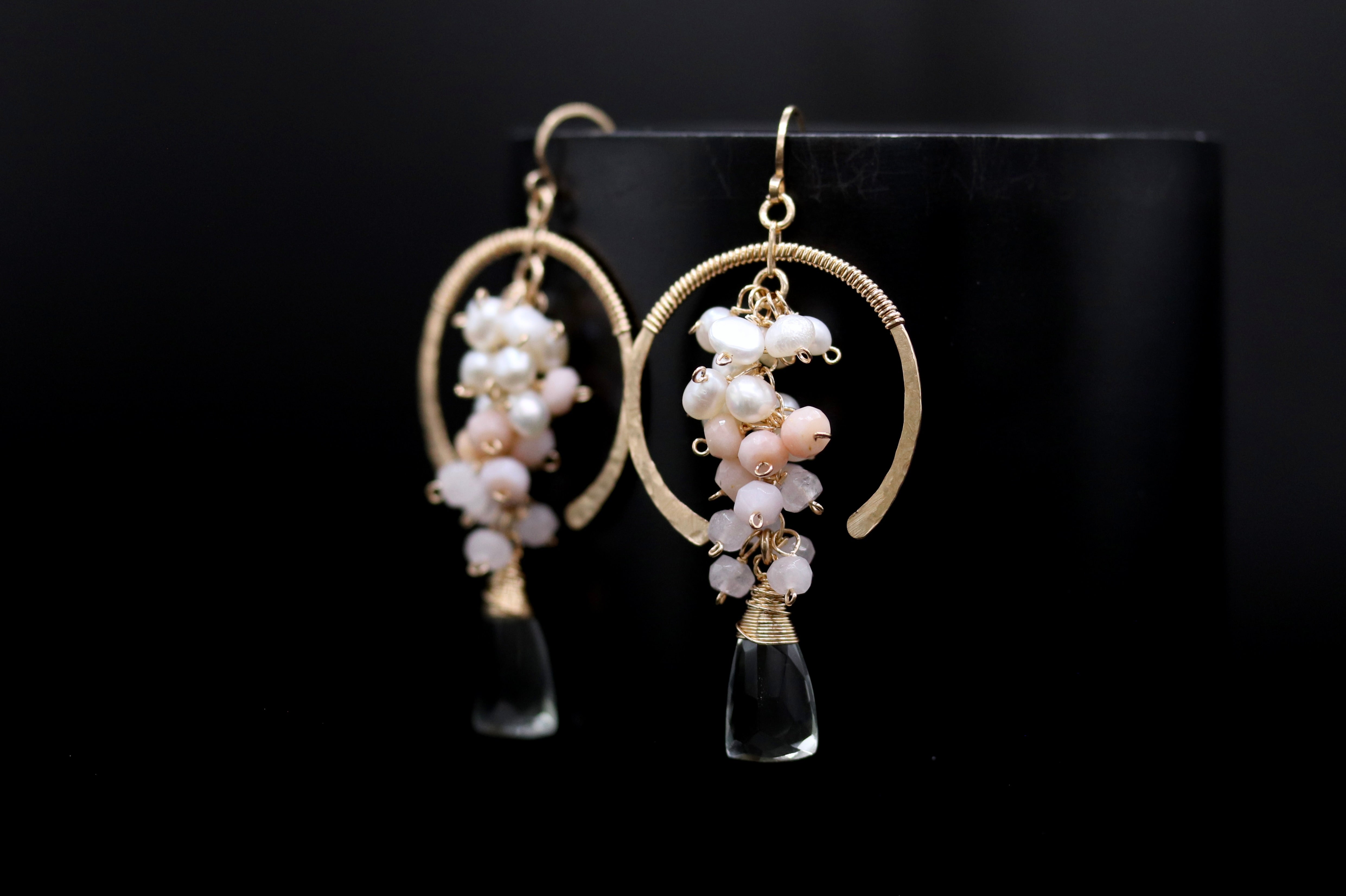 A pair of elegant earrings with a clear crystal pendant and a floral design, featuring white and pink beads.