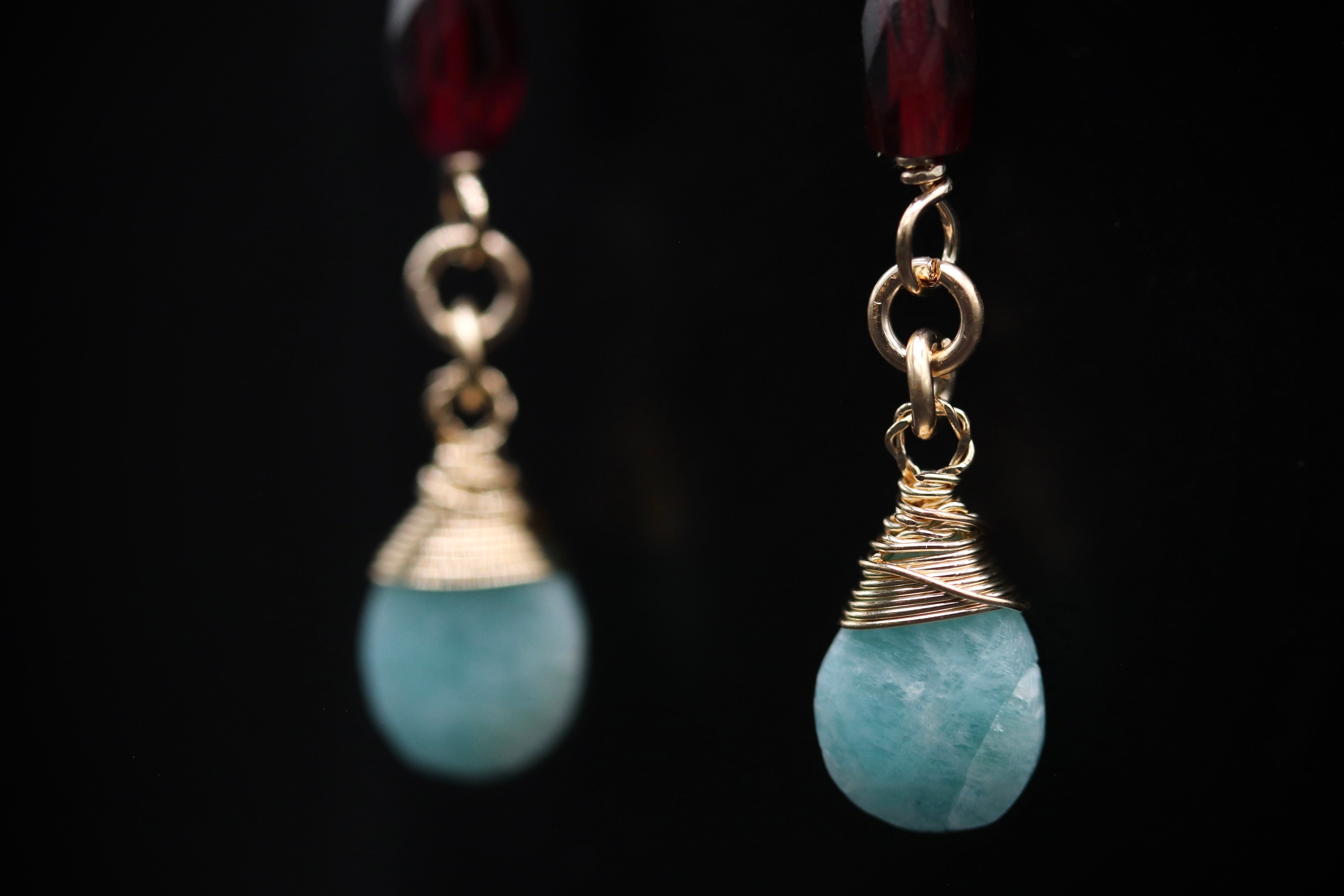 A close-up view of a pair of earrings with blue gemstones and gold-colored metal chains.