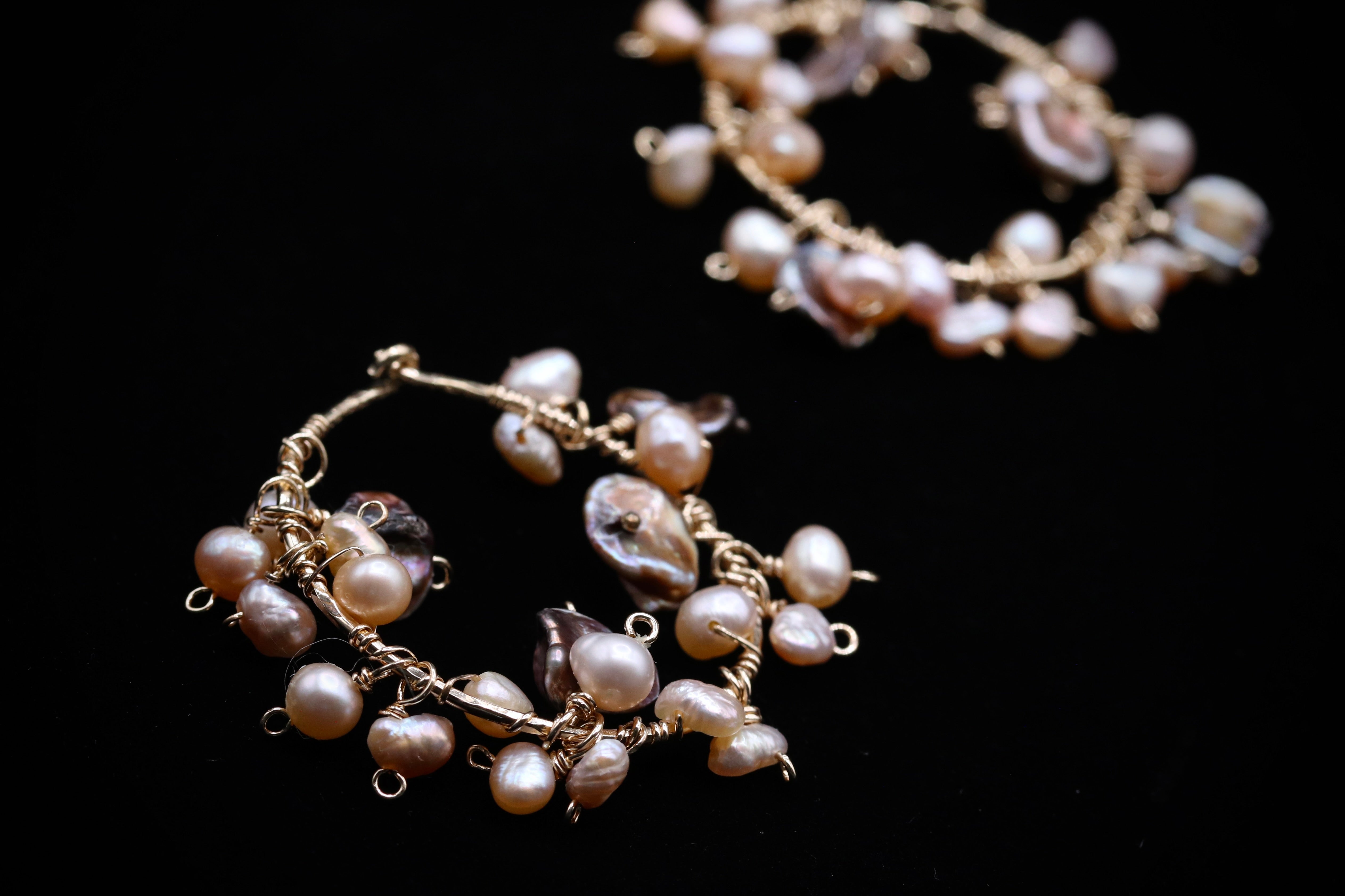 A close-up image of a pair of earrings made of small, round, white pearls with gold-colored metal accents.