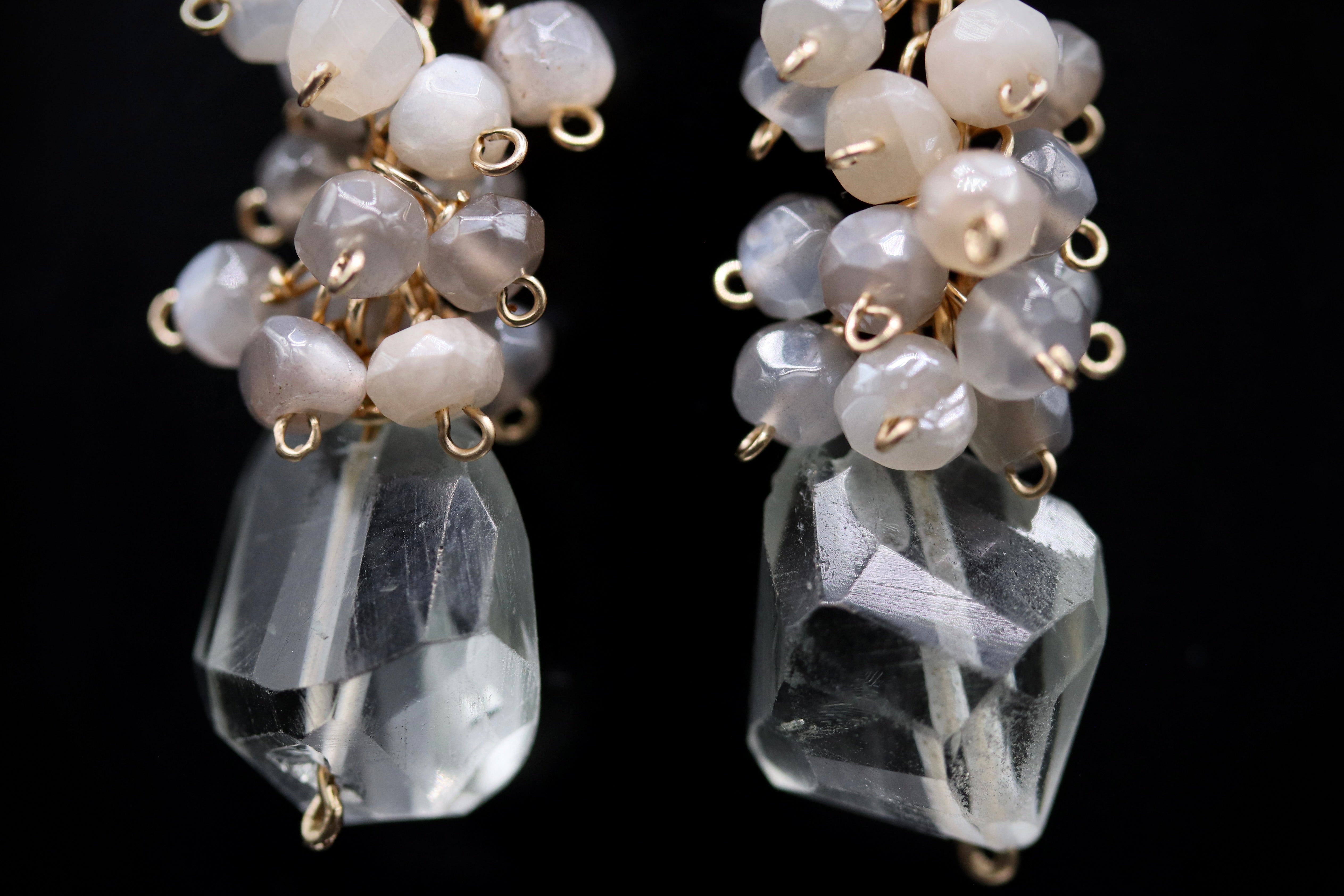 A close-up view of a pair of crystal earrings with clear gemstones and metal chains.