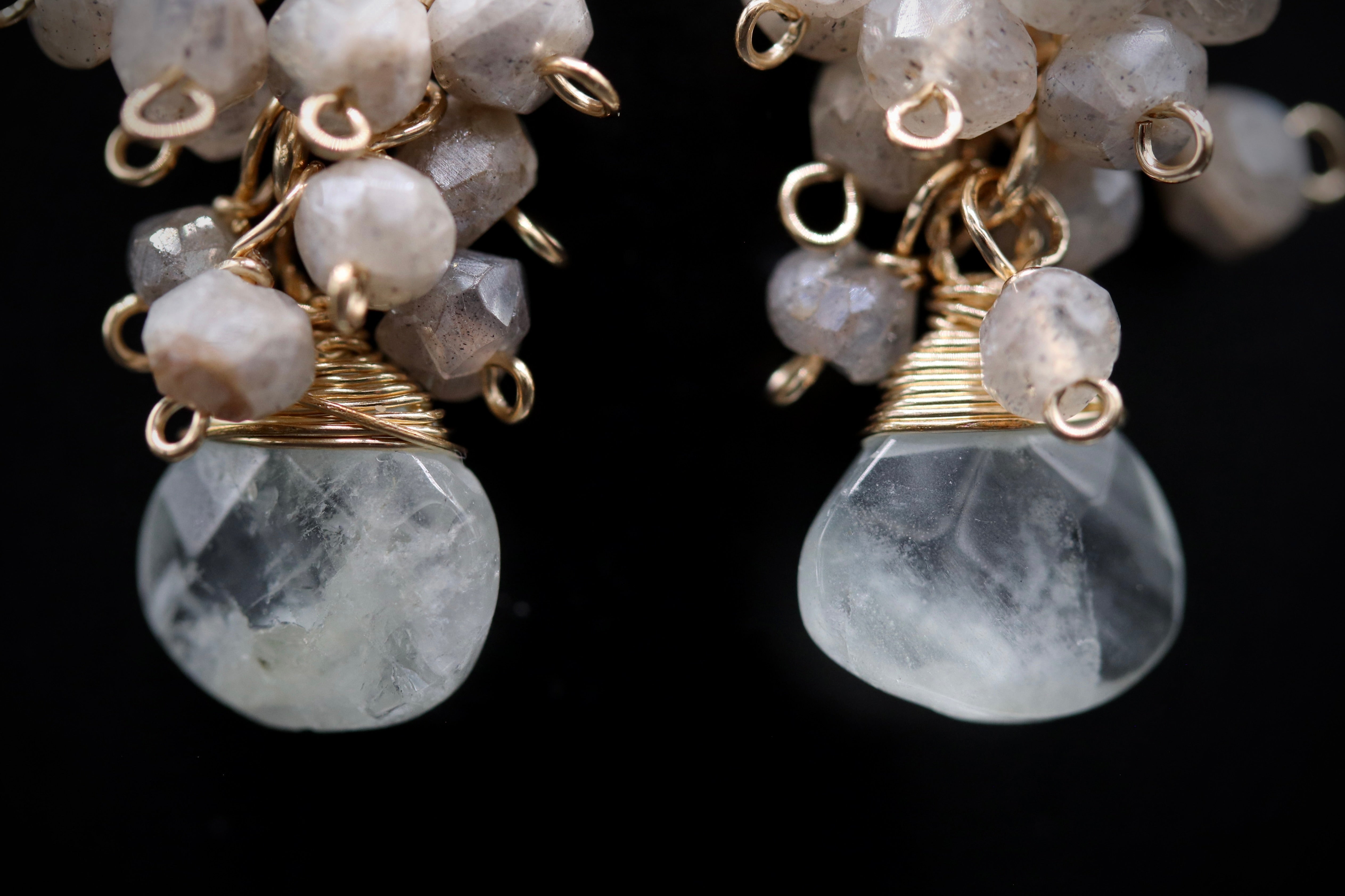 A close-up image of a pair of earrings with clear crystal stones and gold-colored metal accents.
