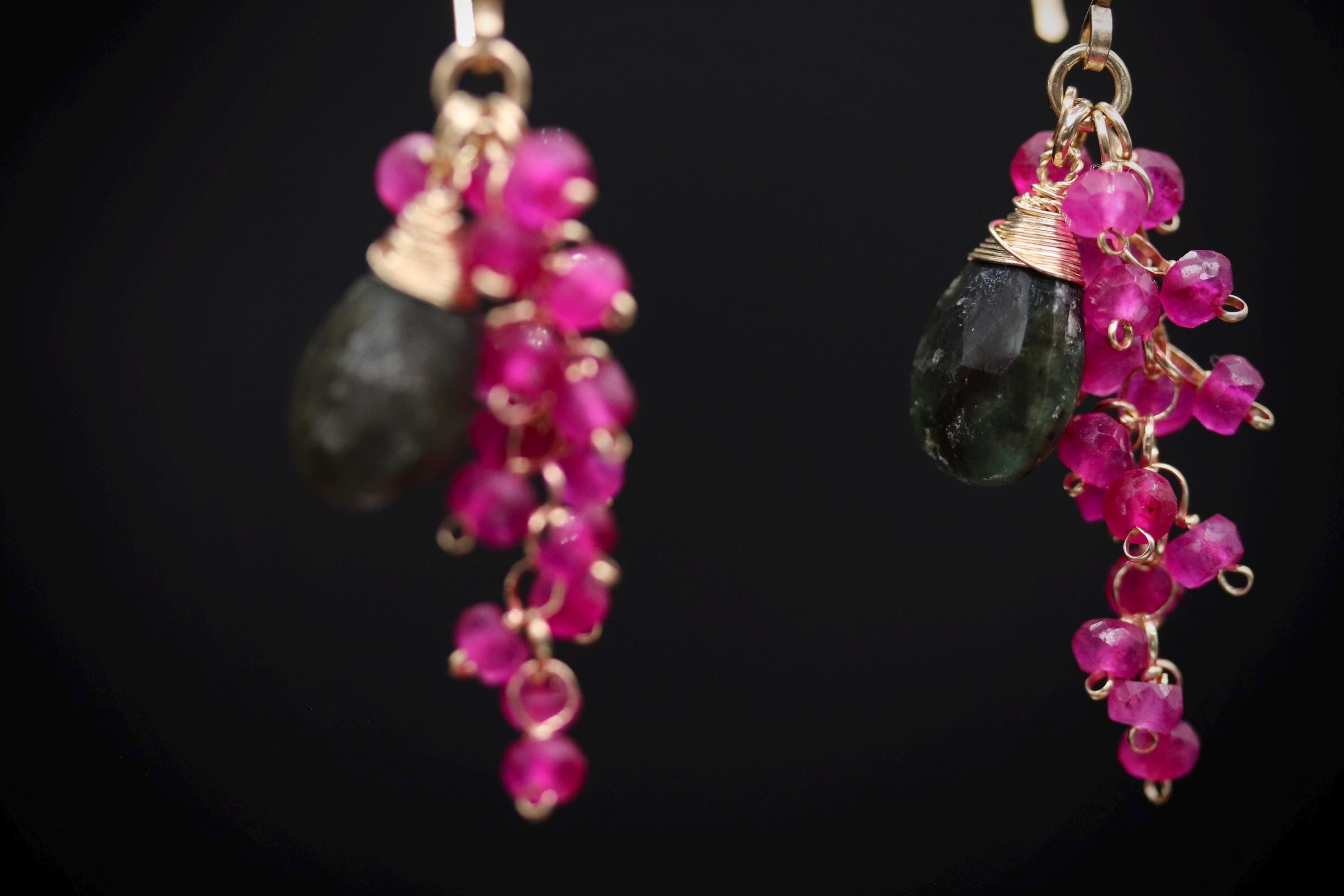 A pair of earrings with a combination of black and pink gemstones, as well as dangling beads in shades of pink.