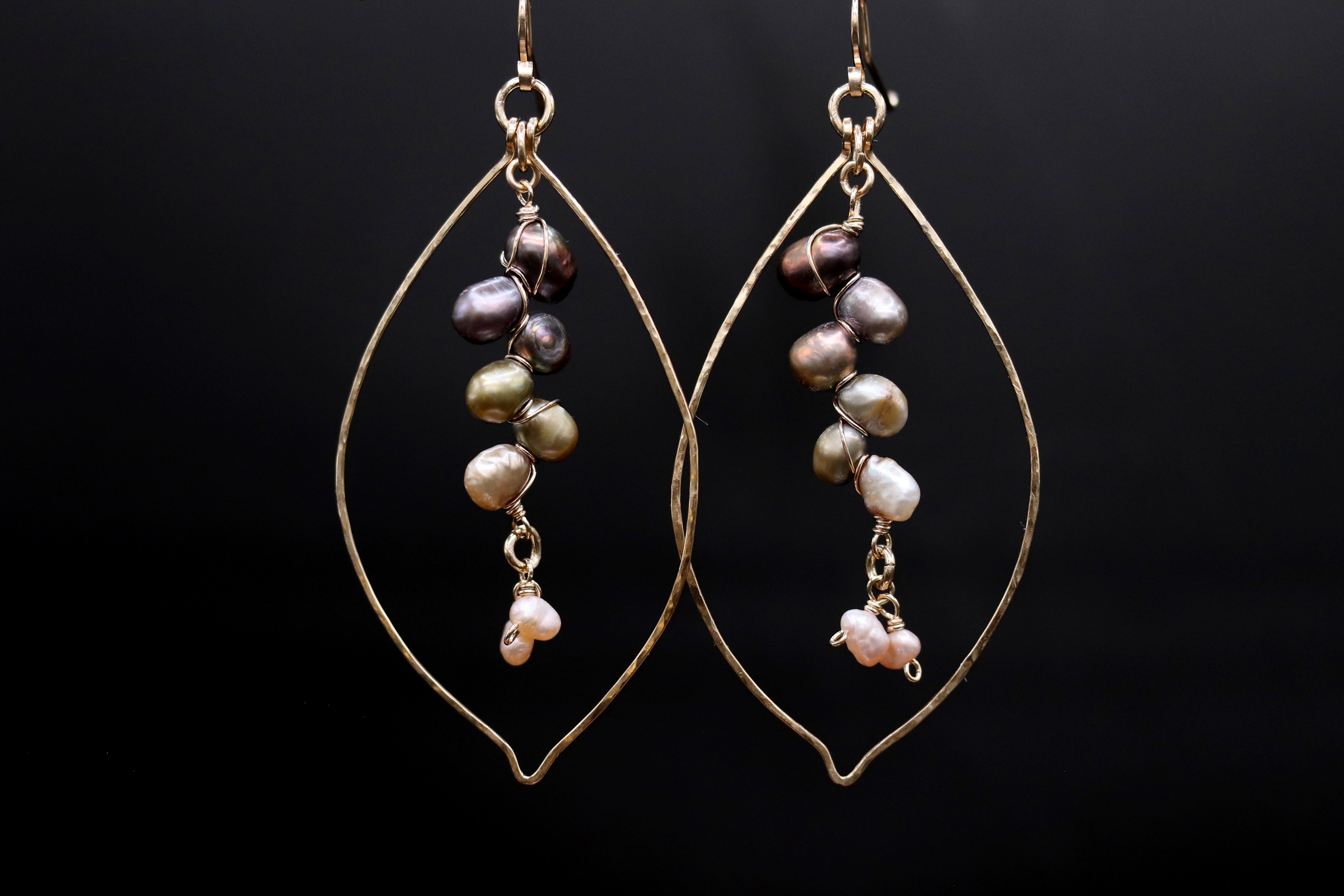 A pair of earrings with a leaf-shaped design, featuring a combination of pearls and beads.