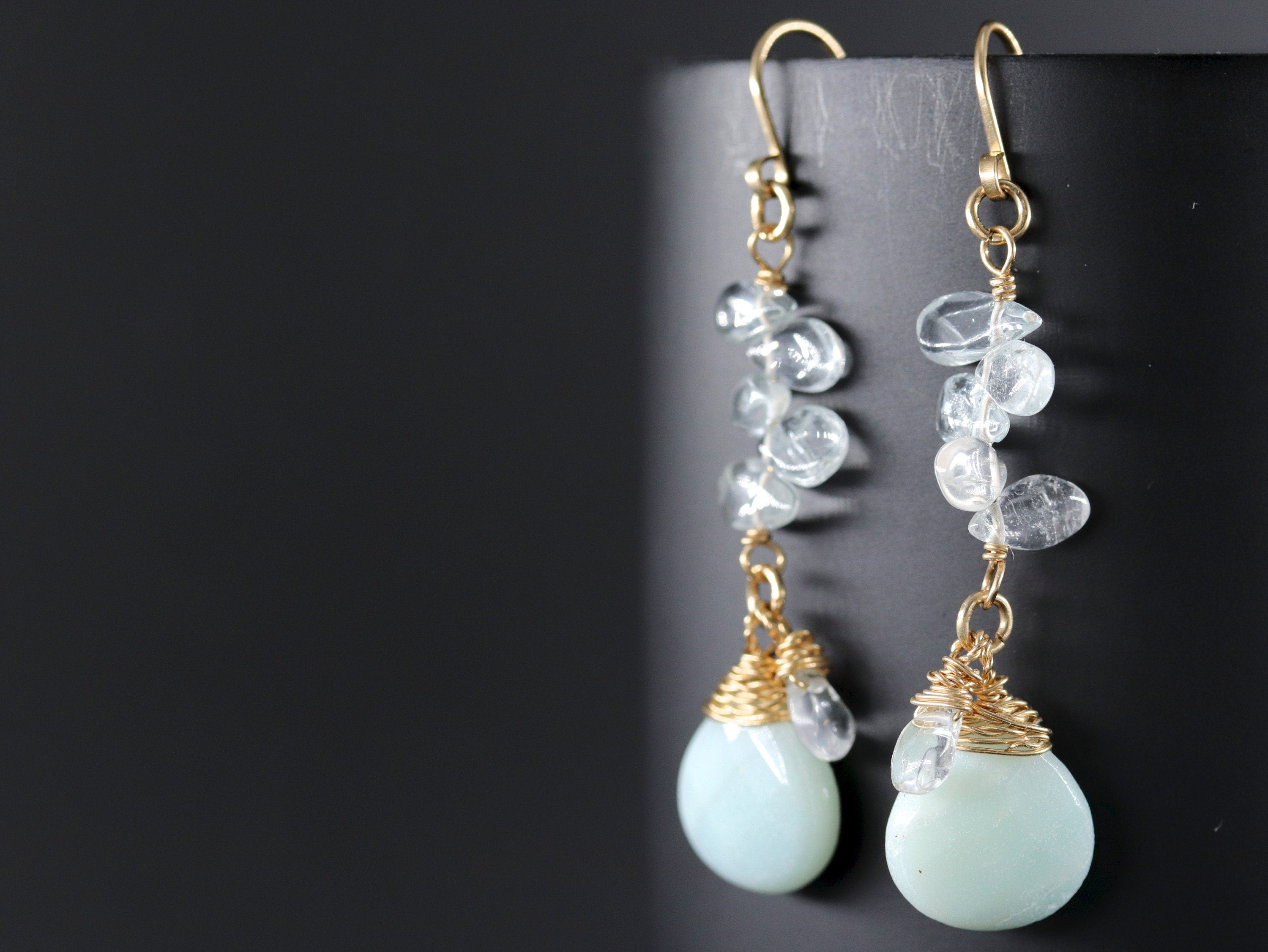 May include: Gold earrings with a teardrop-shaped aquamarine stone and a cluster of clear quartz crystals.