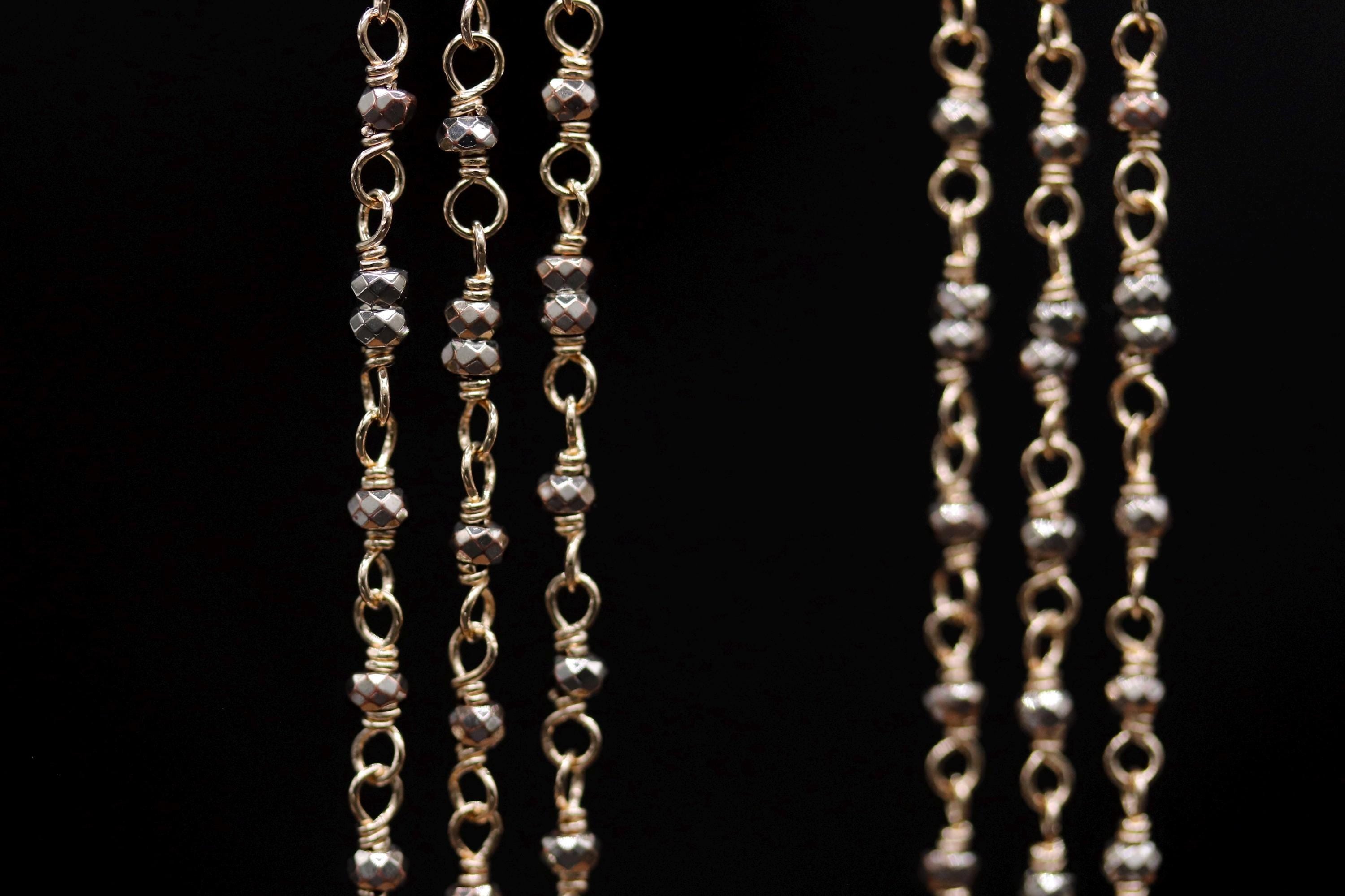 A close-up view of a series of gold-colored metal chains with small, round beads attached to them, creating a visually striking and intricate design.