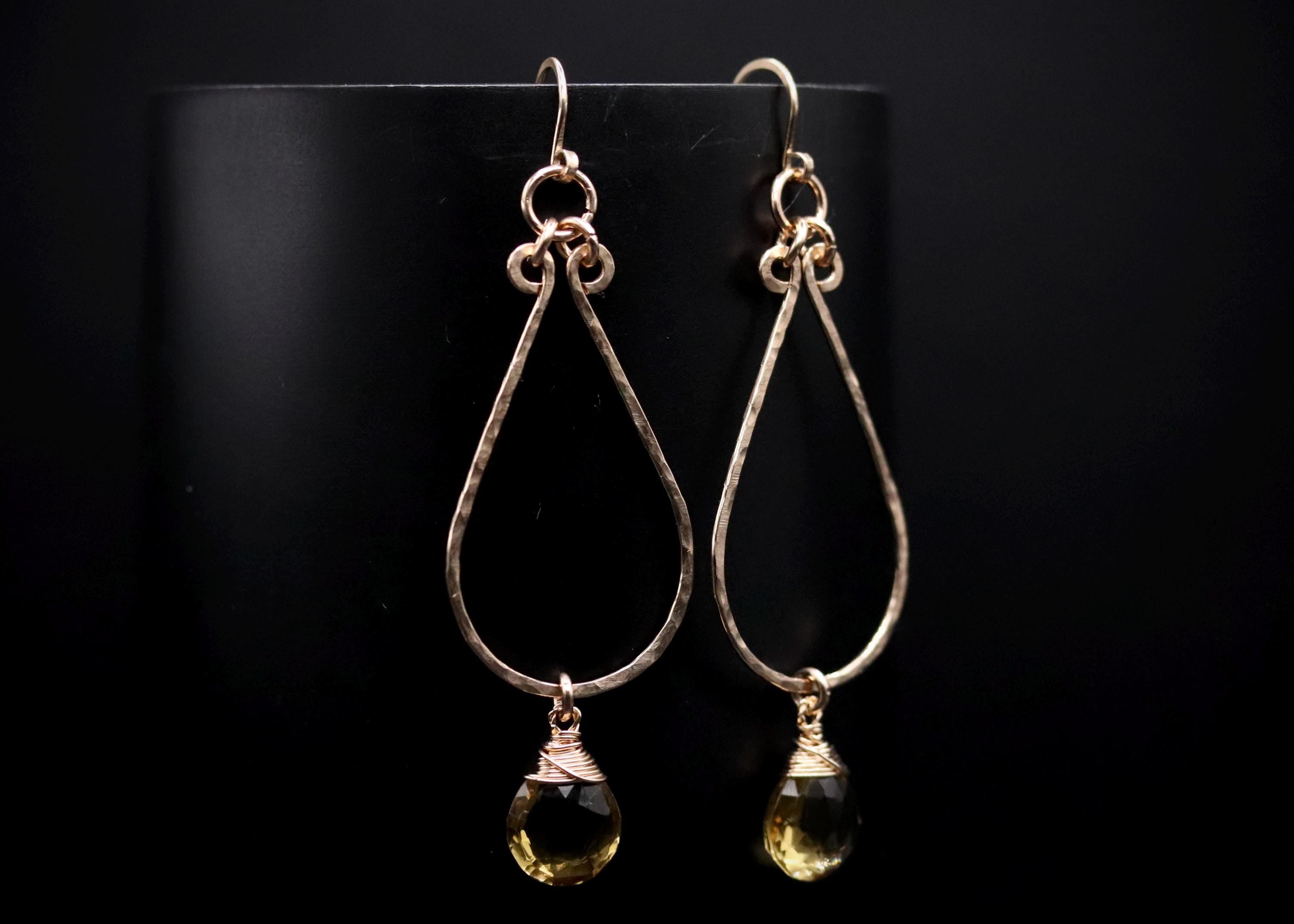 A pair of gold earrings with a yellow gemstone hanging from each earring.