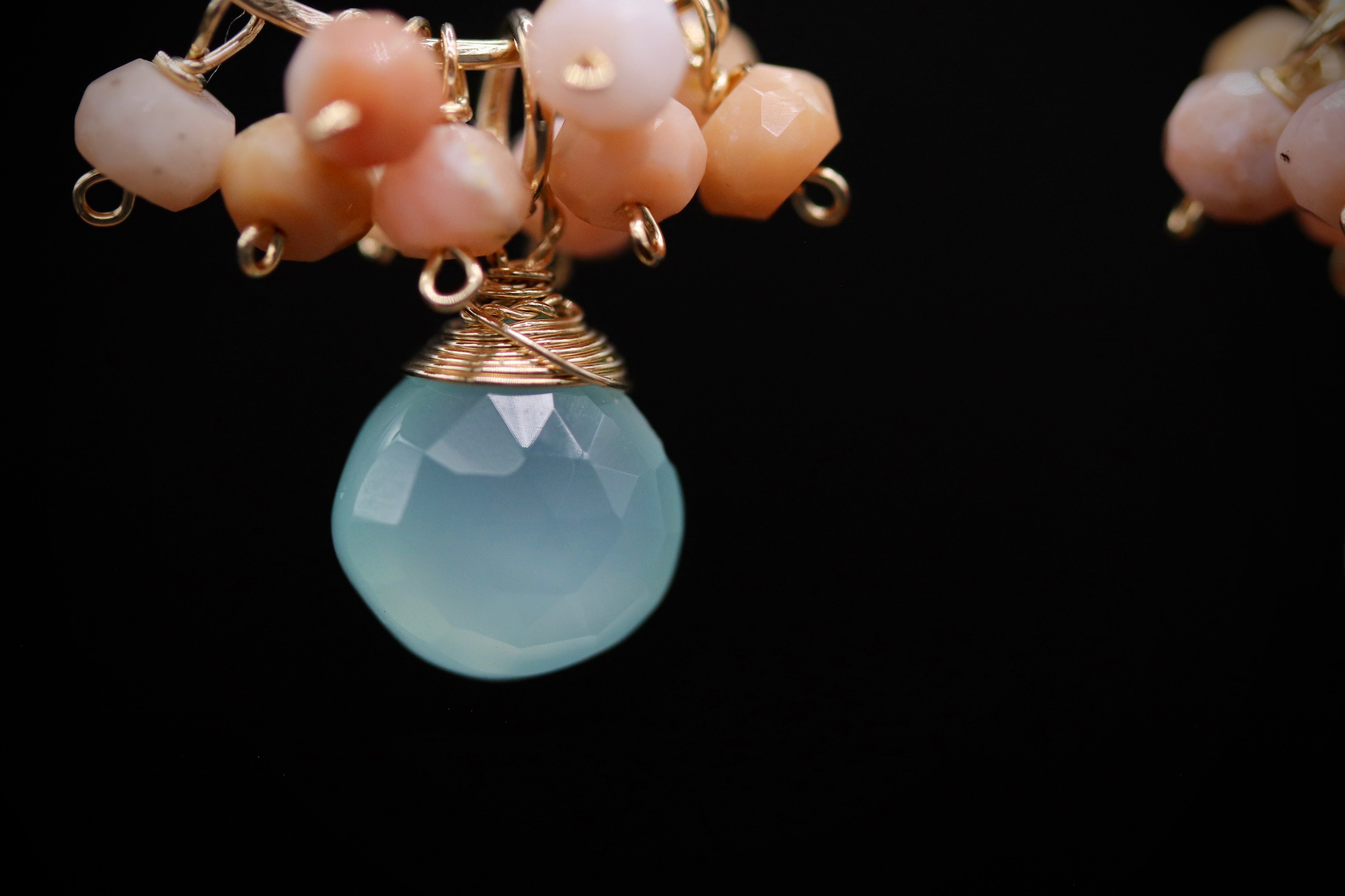 A close-up view of a light blue stone pendant with a gold-colored metal clasp, surrounded by a cluster of small, multicolored beads.