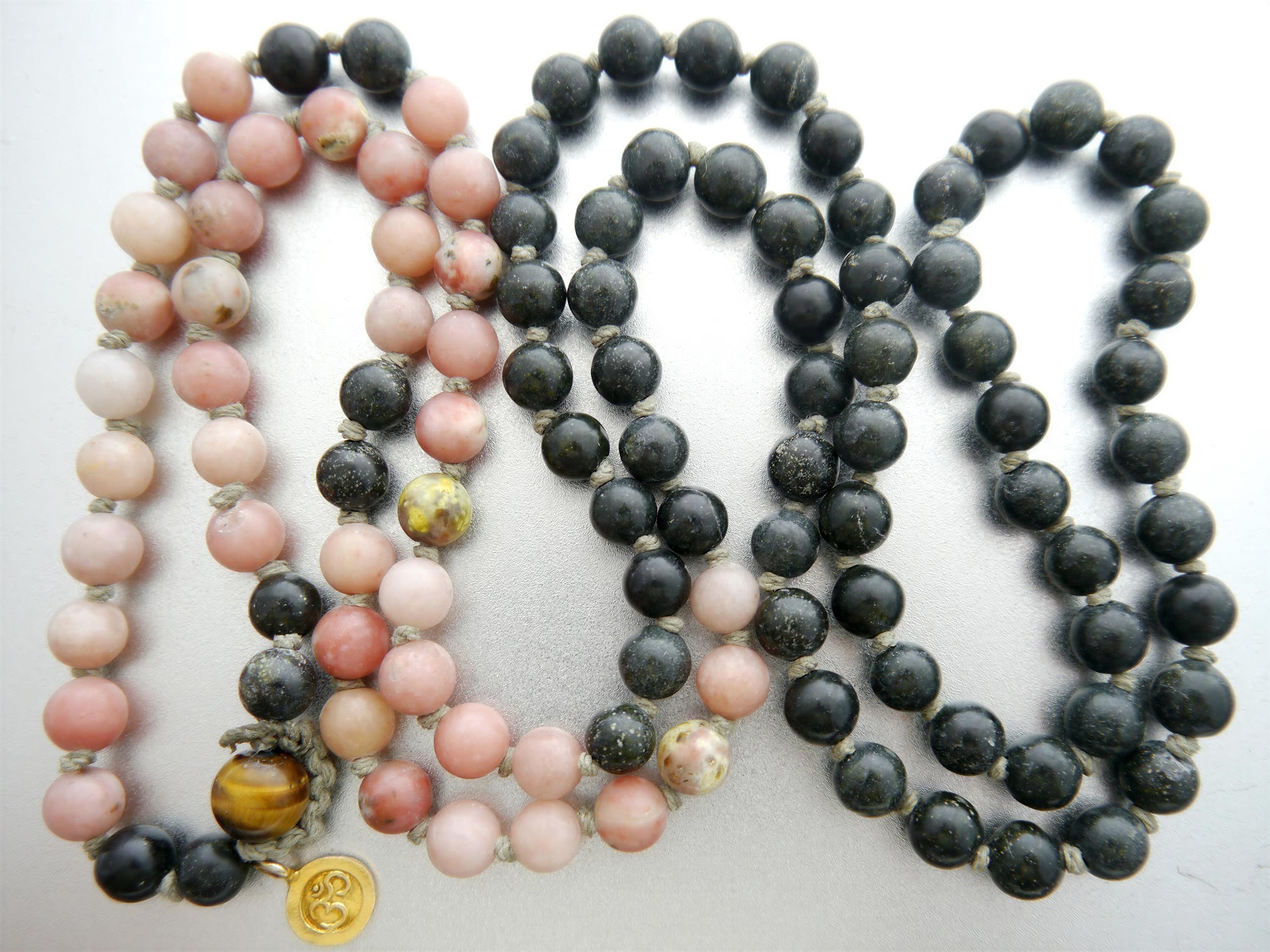 a collection of necklaces with various colored beads, including pink, black, and yellow beads, arranged in a row.