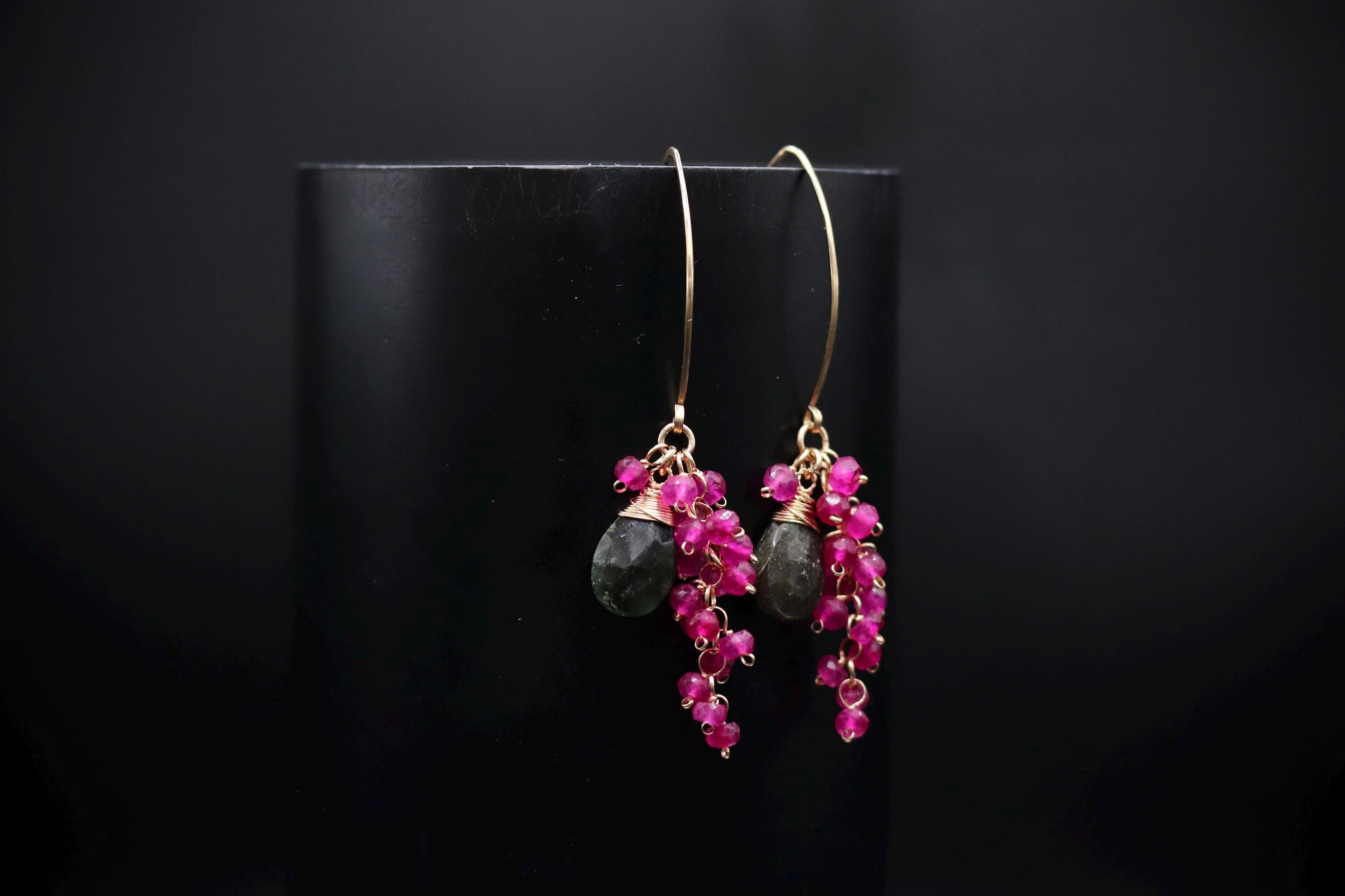 A pair of earrings with a black background and a pair of dangling earrings with red gemstones.
