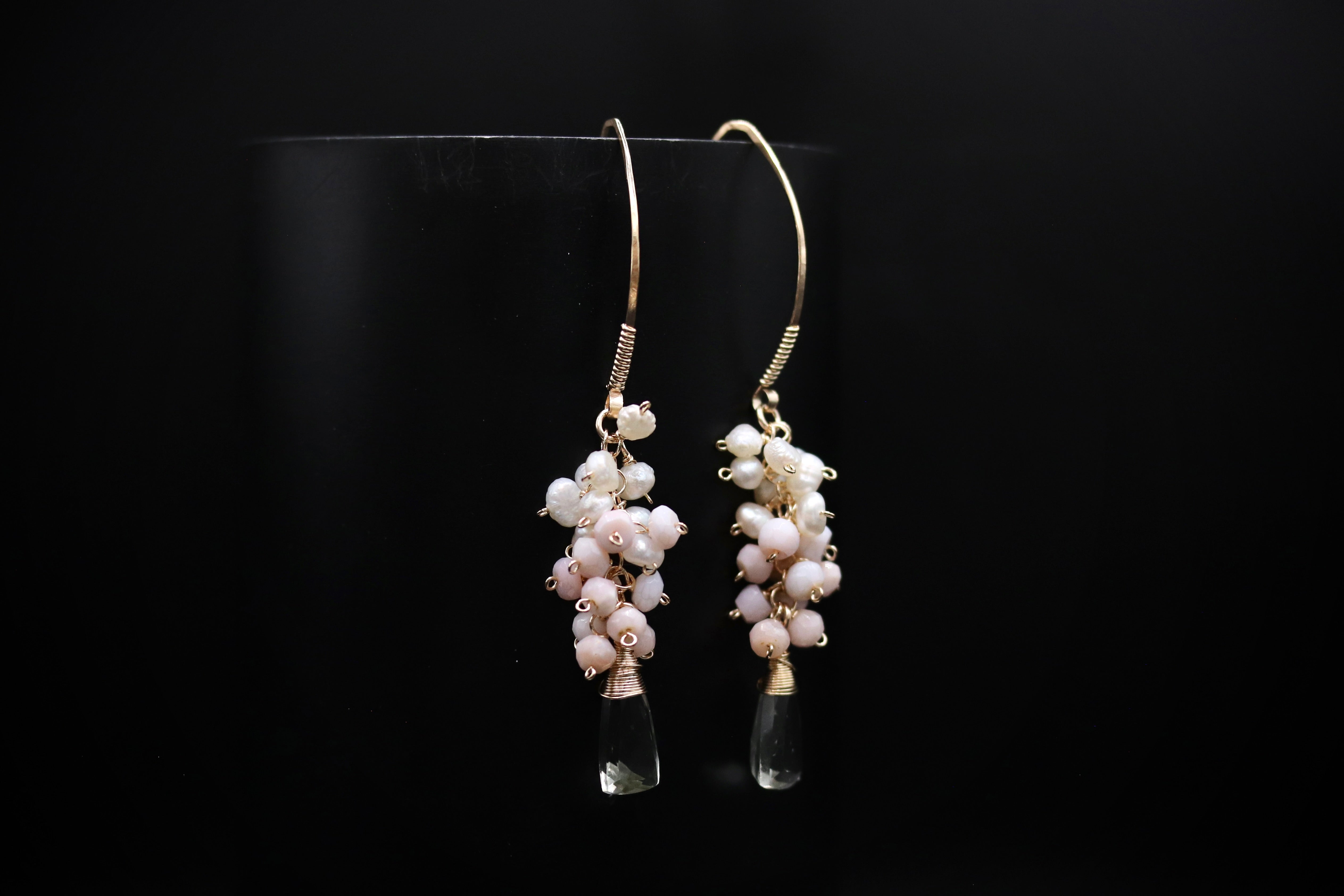 A pair of elegant earrings with clear glass tassels and white pearl beads hanging from the ends.
