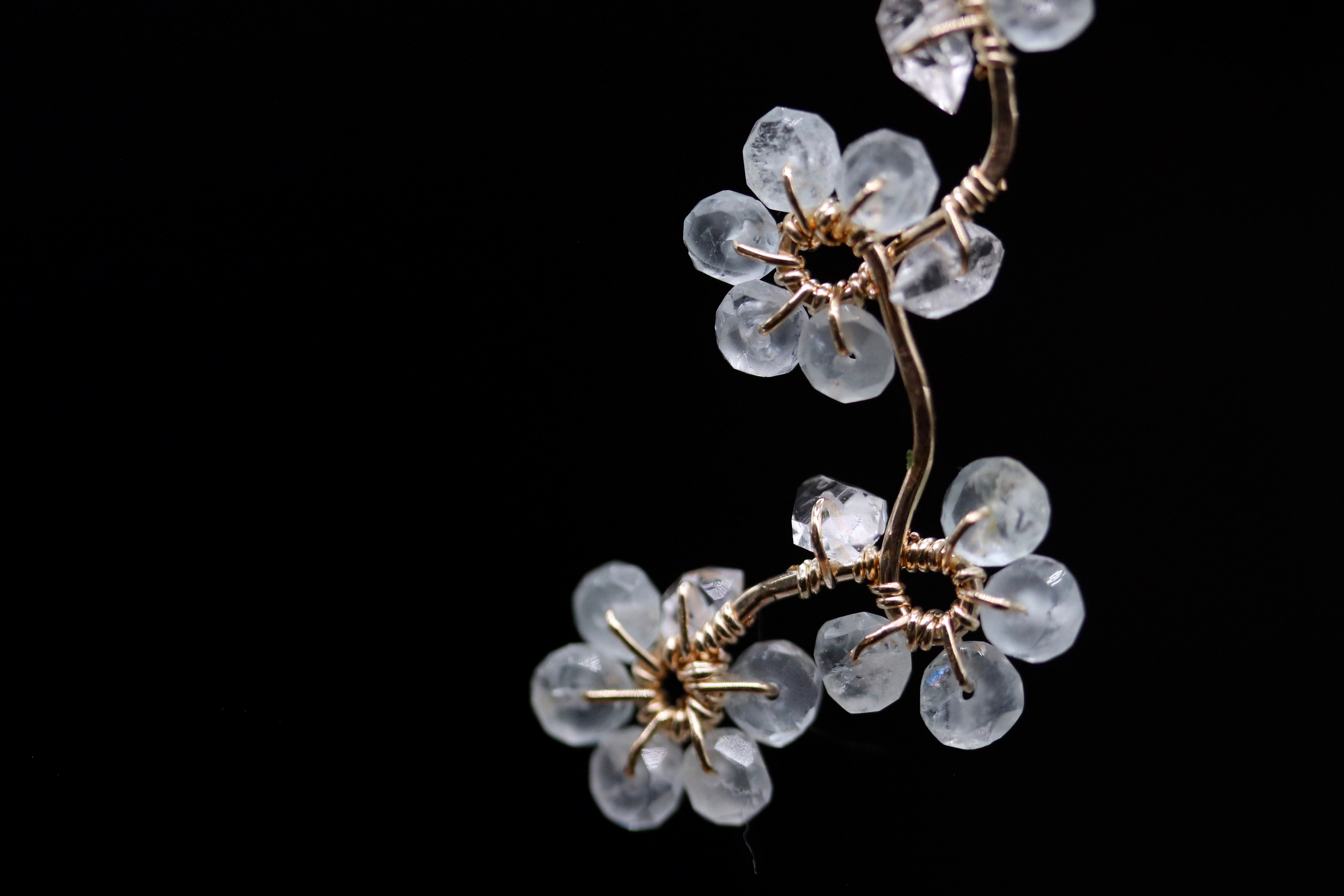 A close-up view of a delicate, crystal-like flower-shaped wire sculpture against a dark background.