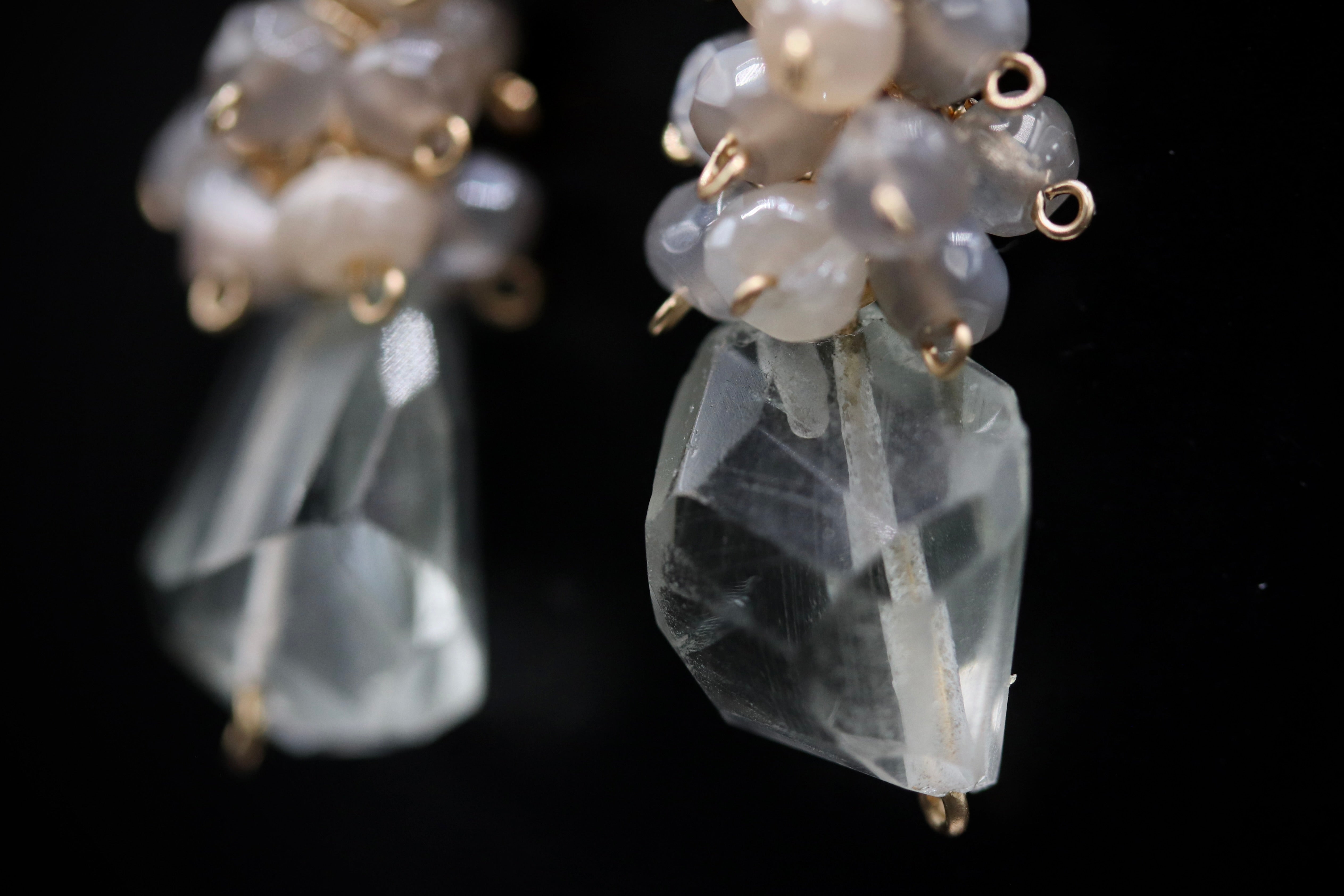 A close-up view of a pair of crystal earrings with clear gemstones and metal hooks.